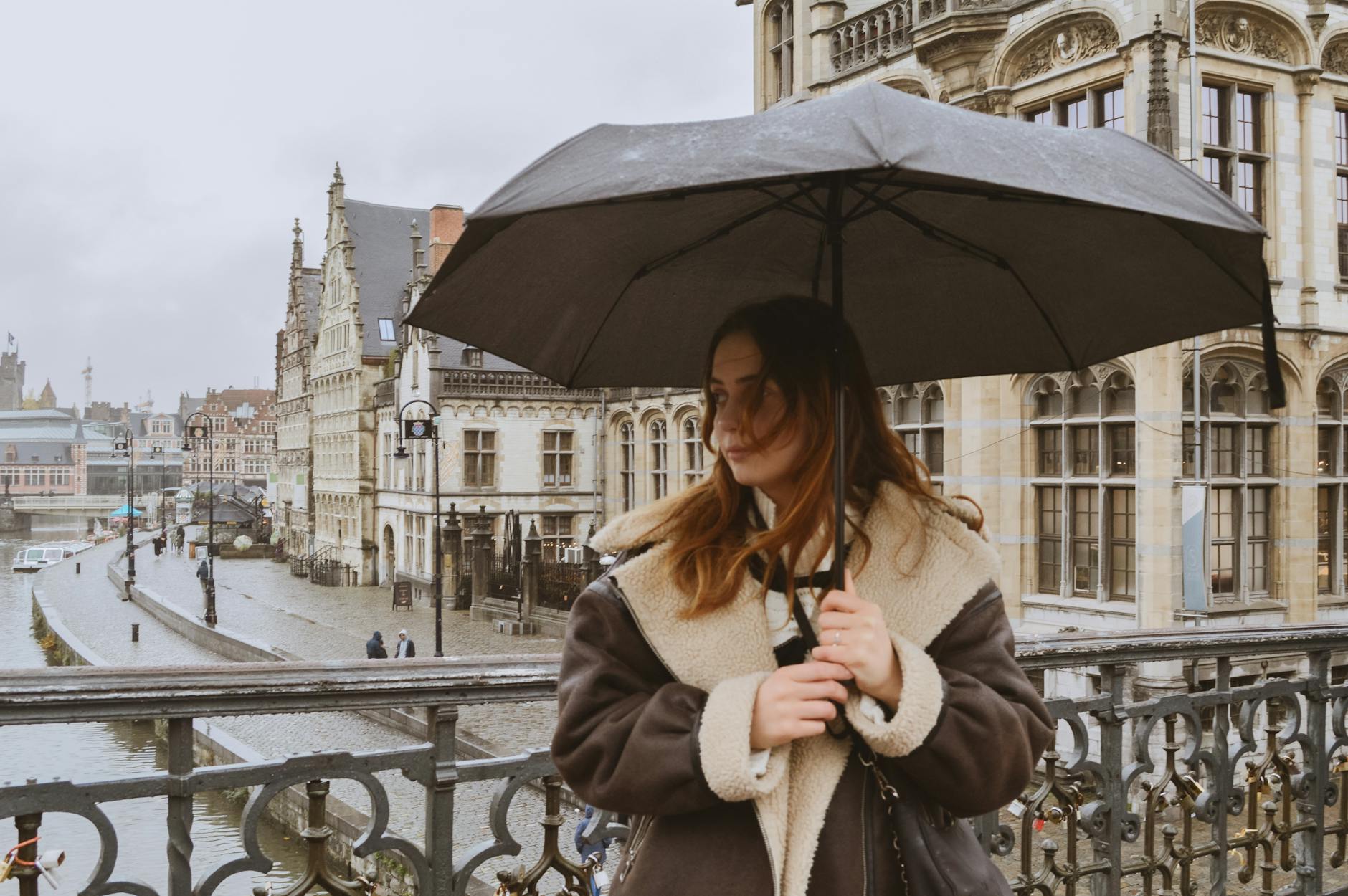 Mujer con paraguas en día lluvioso en una ciudad europea con arquitectura histórica