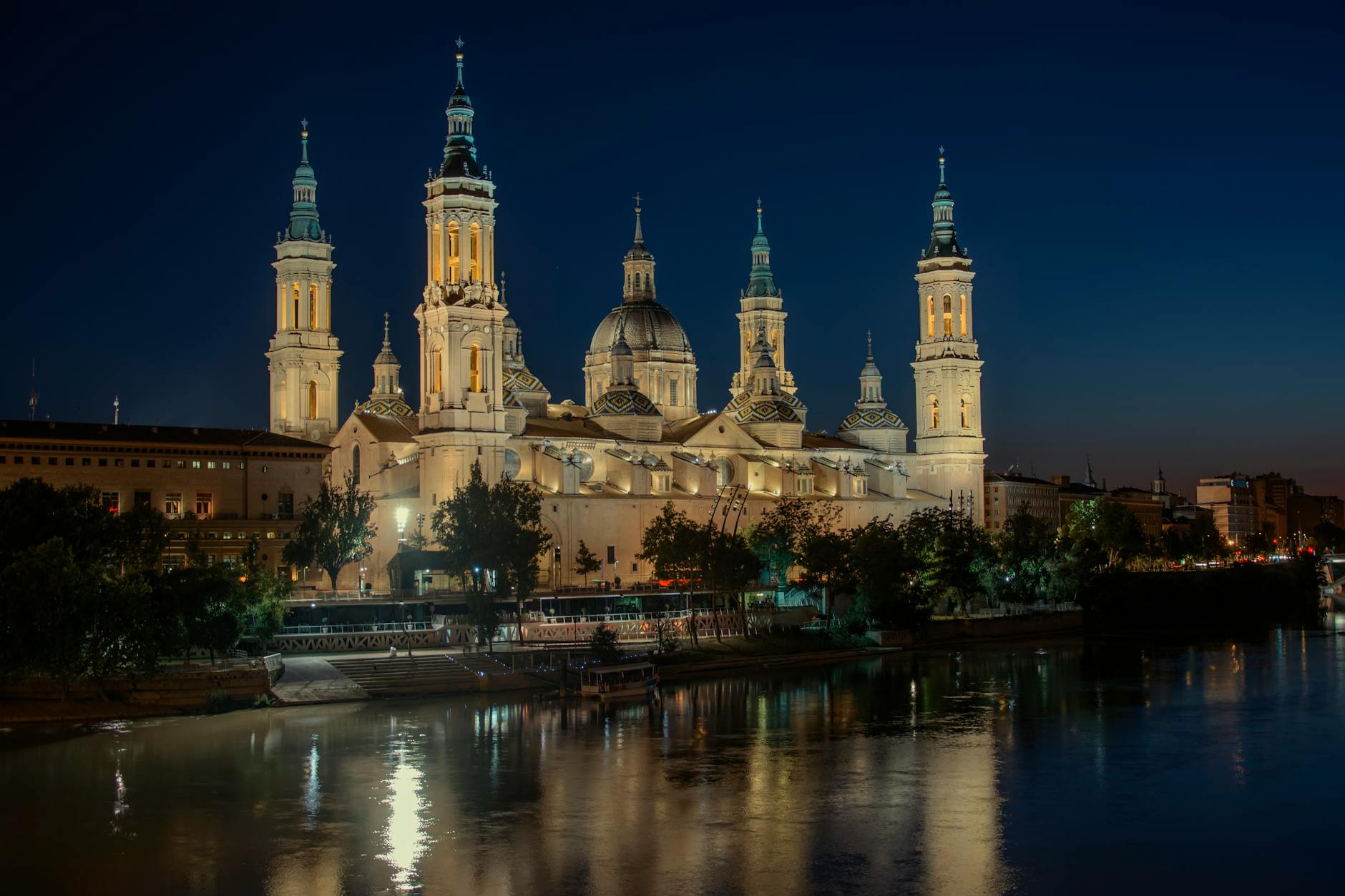 Basilica del Pilar iluminada de noche con reflejos en el rio Ebro