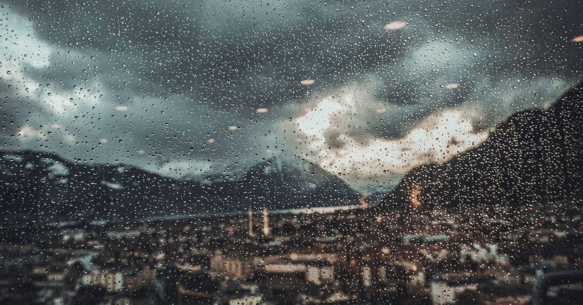 Vista de una ciudad europea a través de una ventana con gotas de lluvia