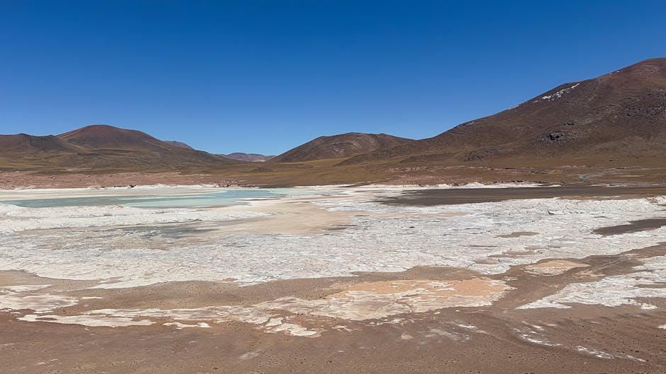 Salar de Uyuni con montañas andinas al fondo bajo cielo azul
