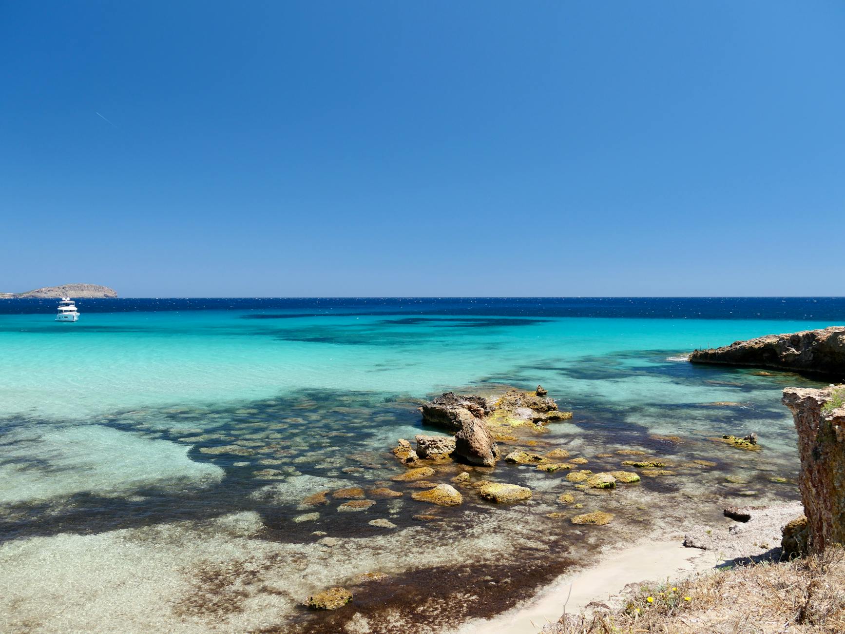 Vista impresionante de las aguas turquesa y la costa rocosa de Ibiza bajo cielo azul