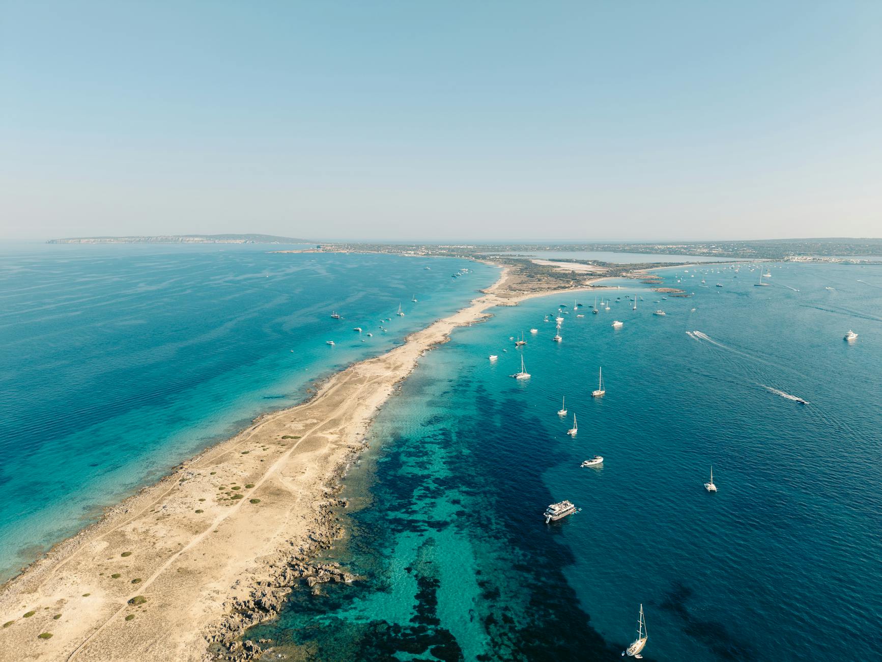 Vista aérea de la costa de Formentera con aguas turquesas y veleros en las Islas Baleares