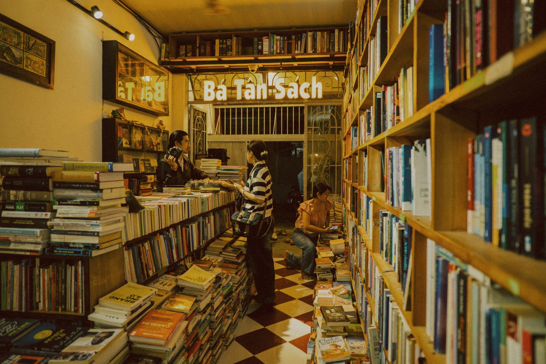 Interior cálido de librería con clientes ojeando libros