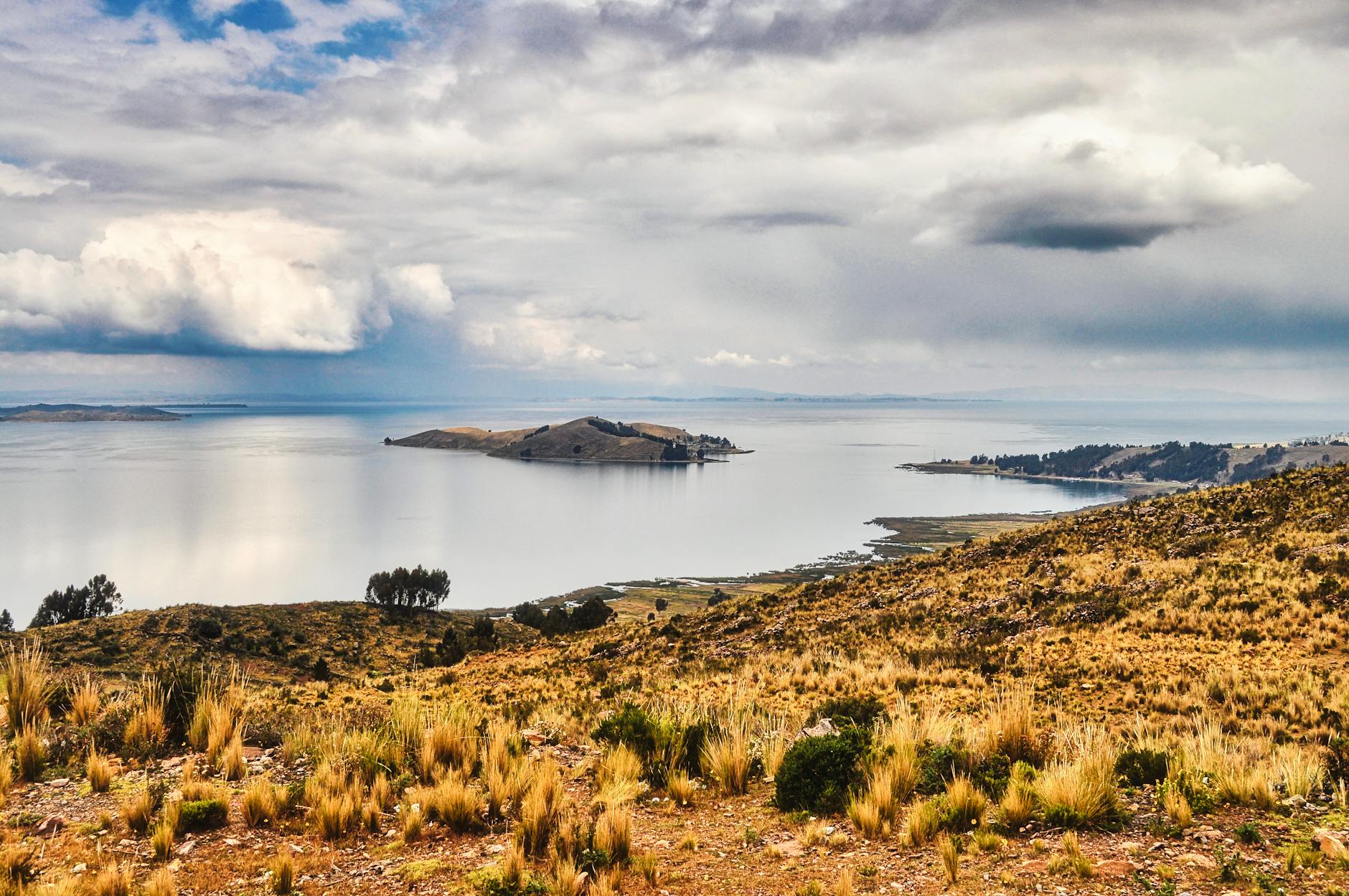Paisaje del lago Titicaca con islas al fondo bajo cielos dramáticos en Puno, Perú