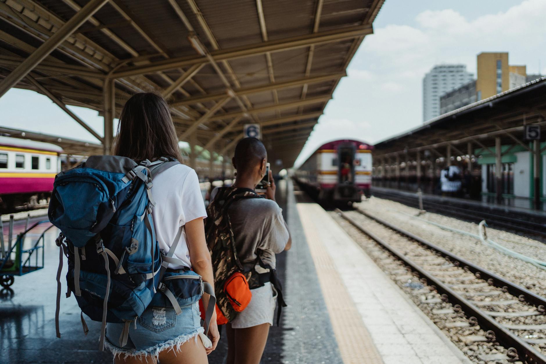 Dos mochileros esperando en una estación de tren, listos para su aventura de viaje