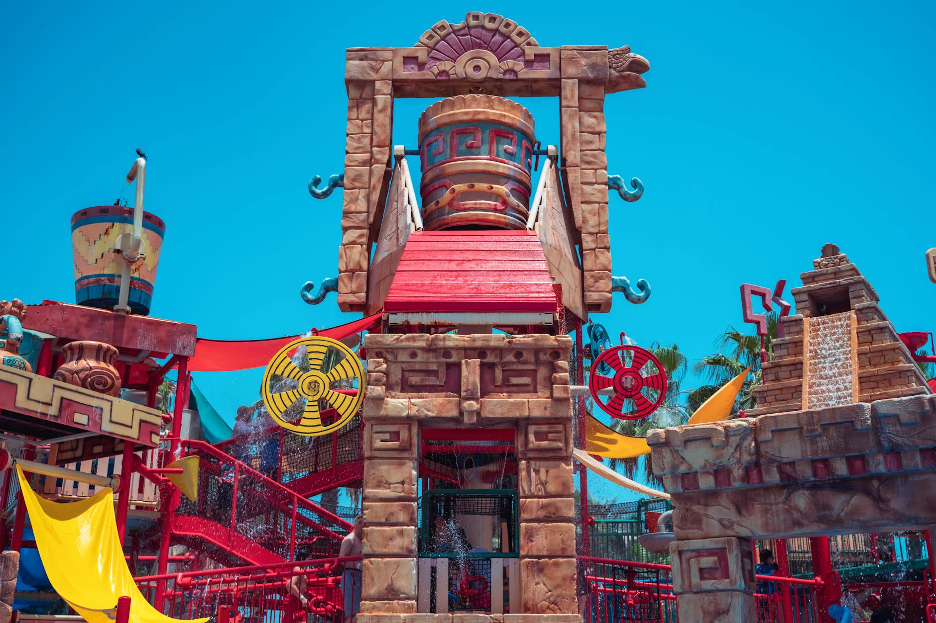 Parque acuático temático con estructuras aztecas y cielo azul de verano