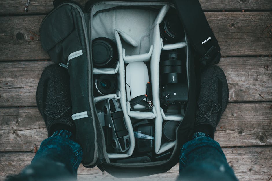 Equipo fotografico organizado en una mochila de viaje sobre fondo de madera