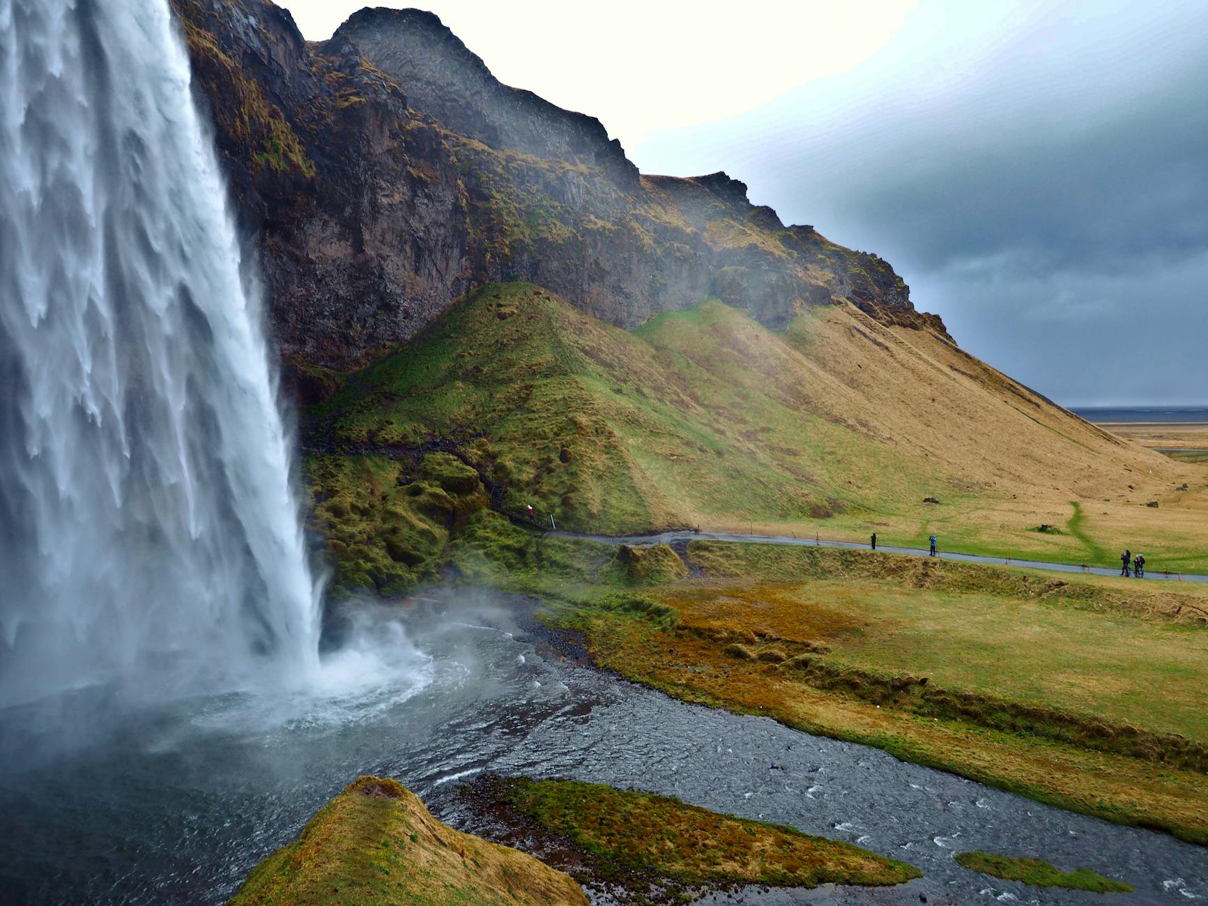 Cascada de Seljalandsfoss cayendo sobre acantilados verdes en Islandia en verano
