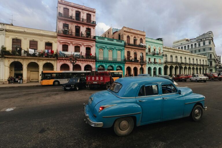 Home Elementor 4 Coches clásicos pasando por edificios coloniales en una calle de La Habana, Cuba