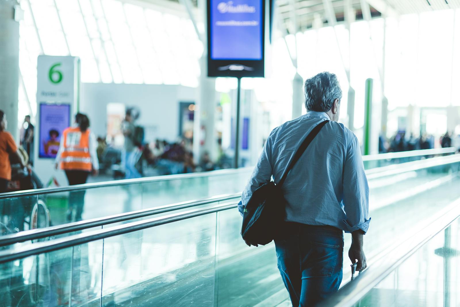Pasajero caminando por terminal de aeropuerto con equipaje de mano