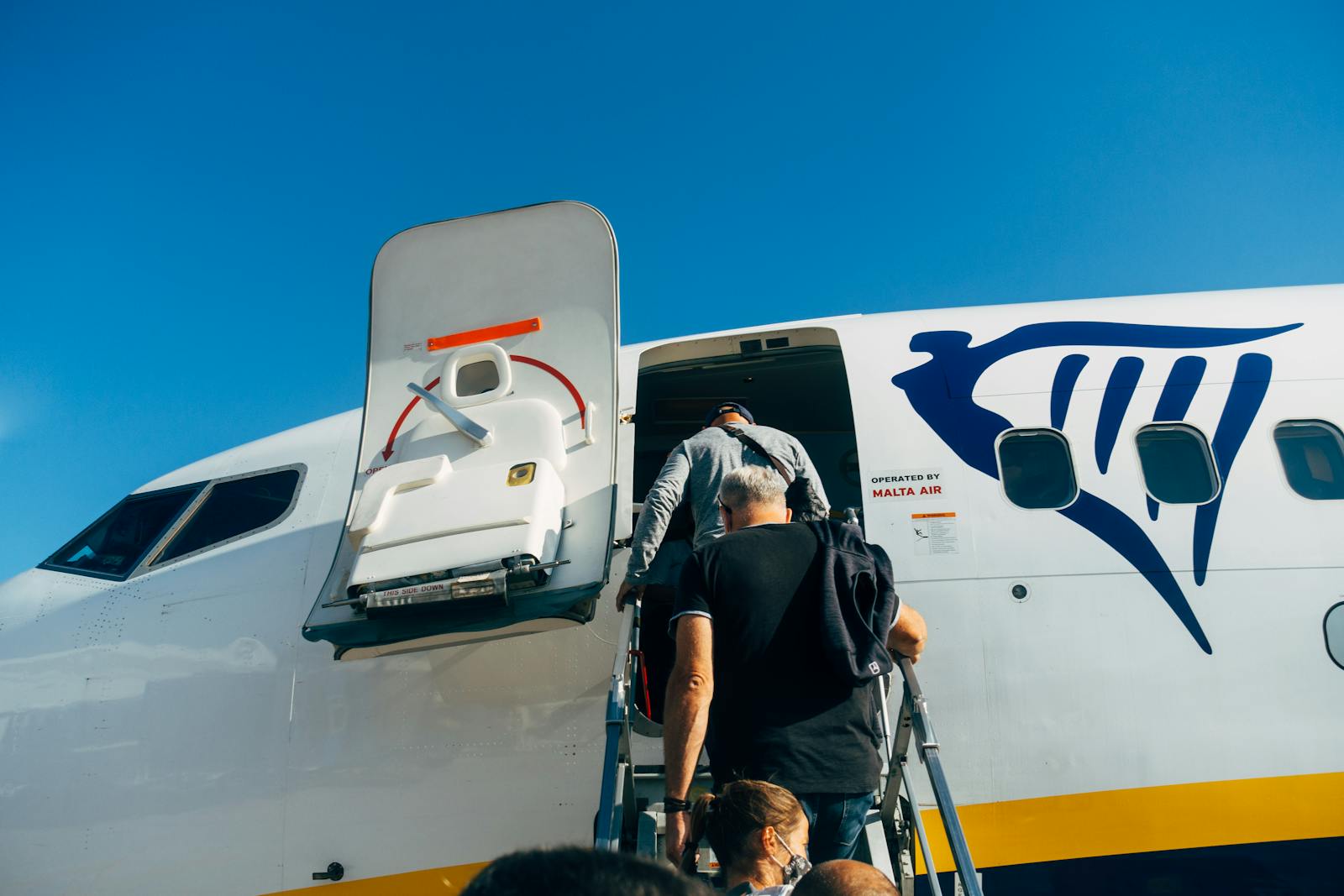 Viajeros subiendo a un avion Ryanair bajo cielo despejado - vuelos baratos low cost