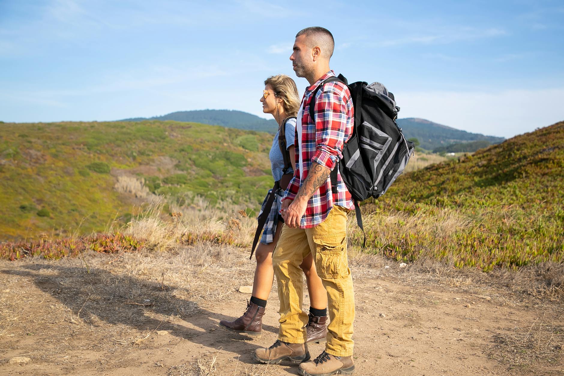 Pareja de peregrinos con mochilas haciendo el Camino Portugues bajo cielo azul