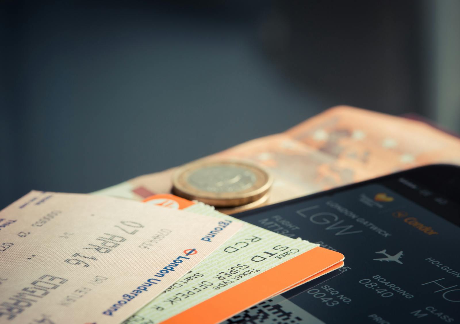 Billete de avion con monedas de euro y movil mostrando detalles de vuelo