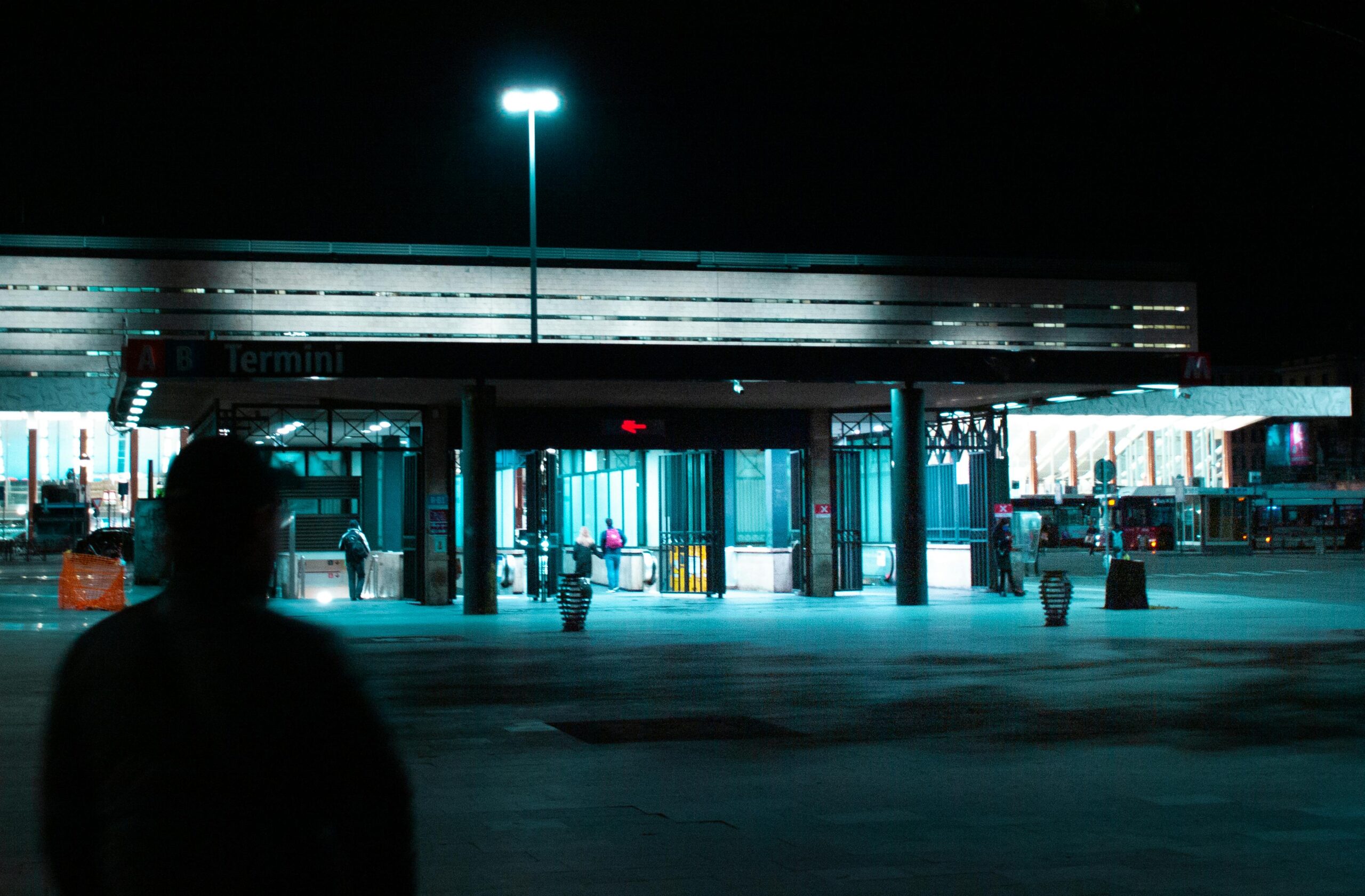 Entrada iluminada de la estacion Roma Termini de noche con viajeros