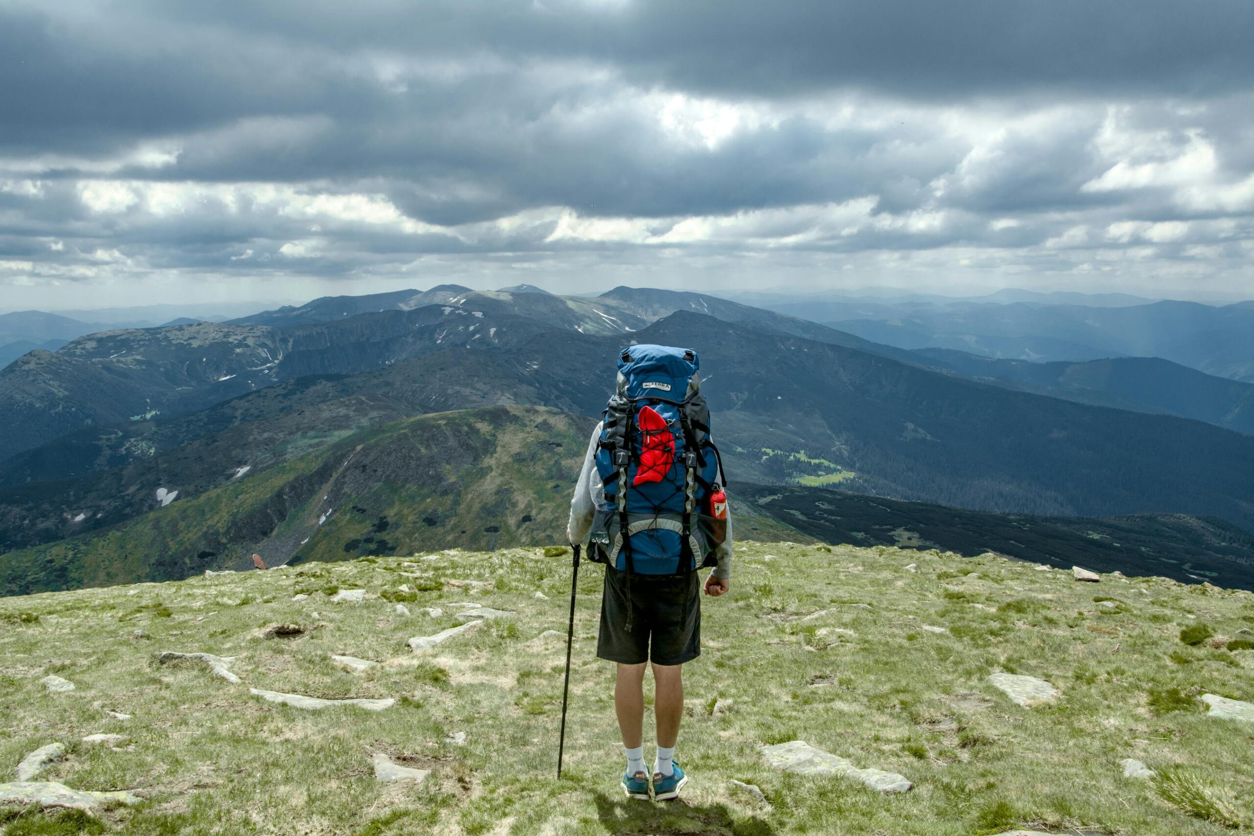 Senderista con mochila caminando por montana nublada
