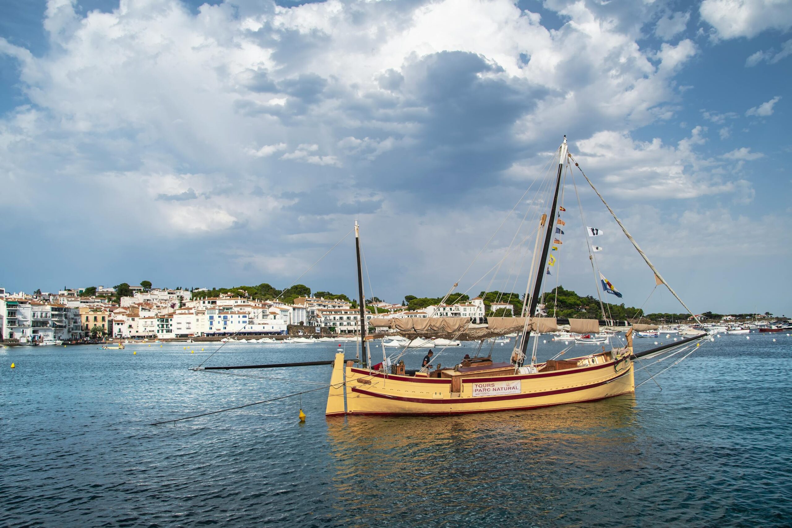 Puerto pesquero de Cadaques con velero tradicional de madera y cielo azul