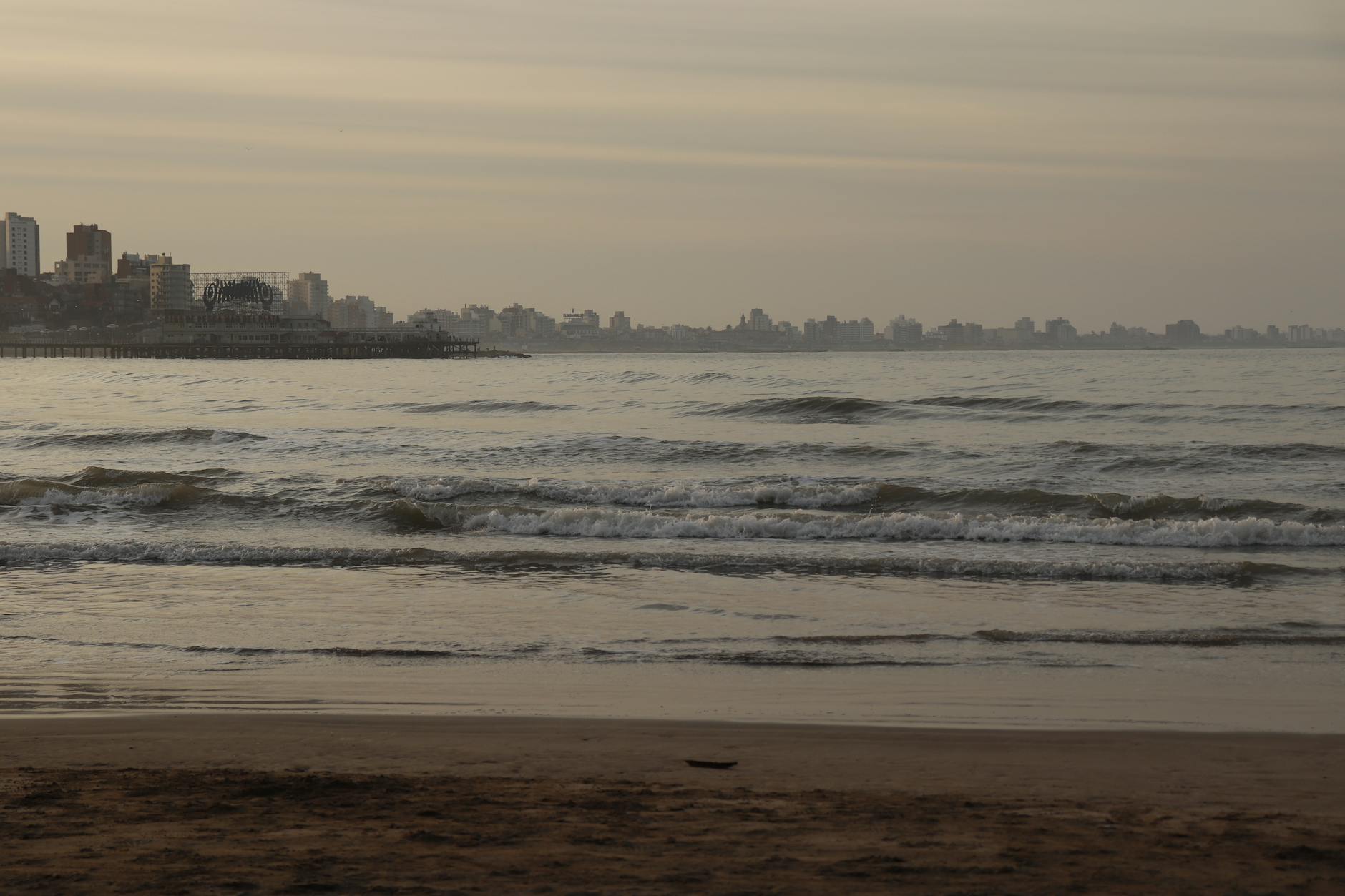 Patrones de olas en la playa con el skyline de Mar del Plata al fondo