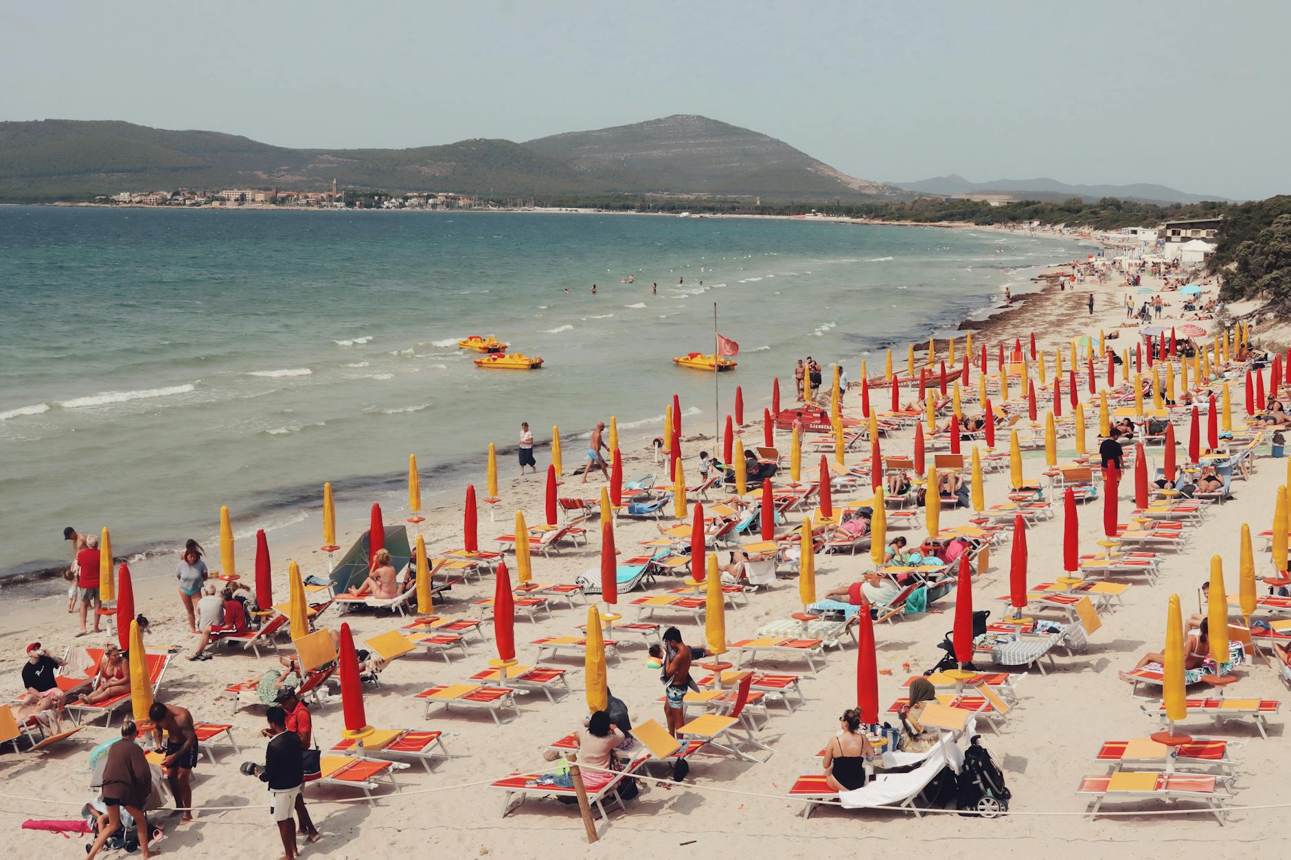 Cerdeña (Sardegna) en 2026: guía honesta de la isla más virgen del Mediterráneo 5 Playa de Alghero en Cerdeña con sombrillas de colores y bañistas