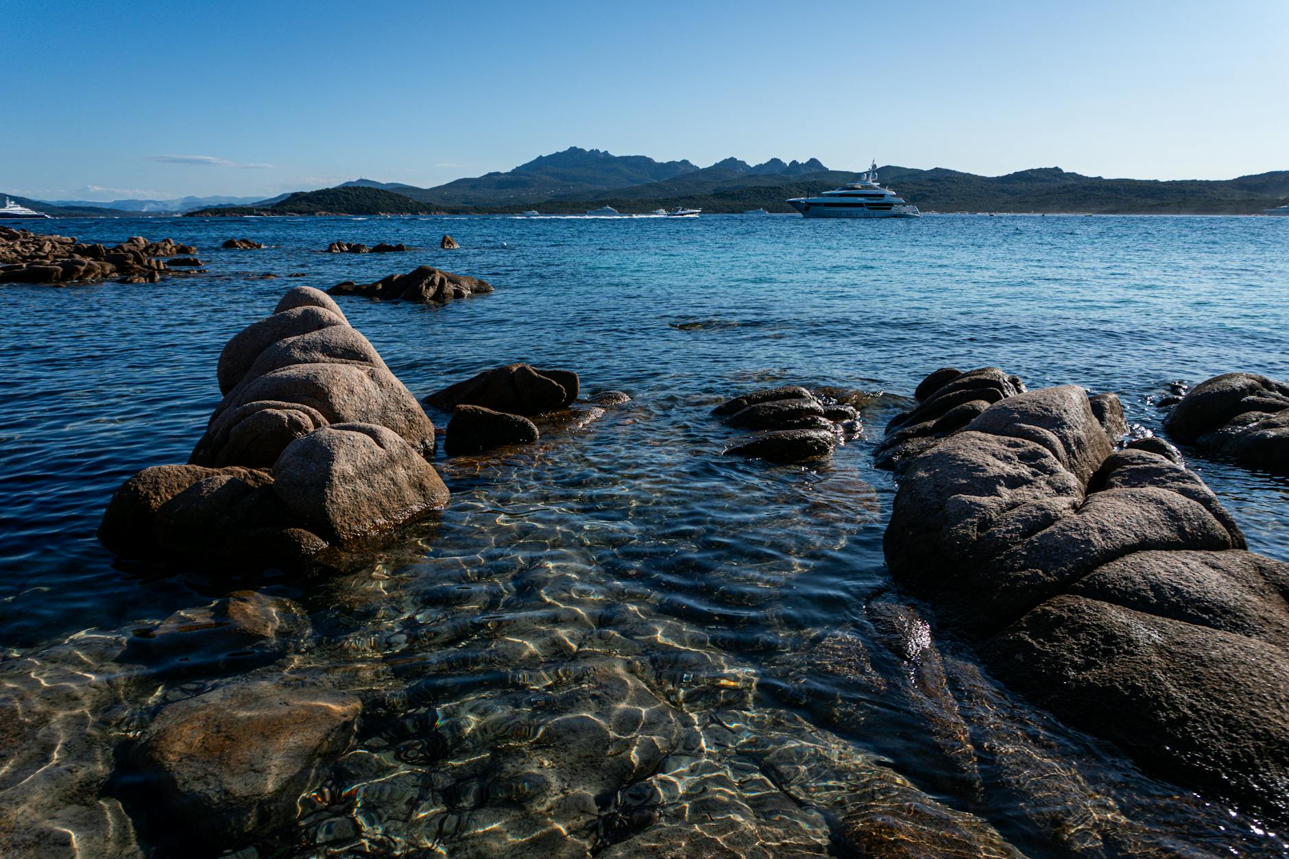 Costa rocosa de Cerdeña con un yate fondeado en aguas turquesa