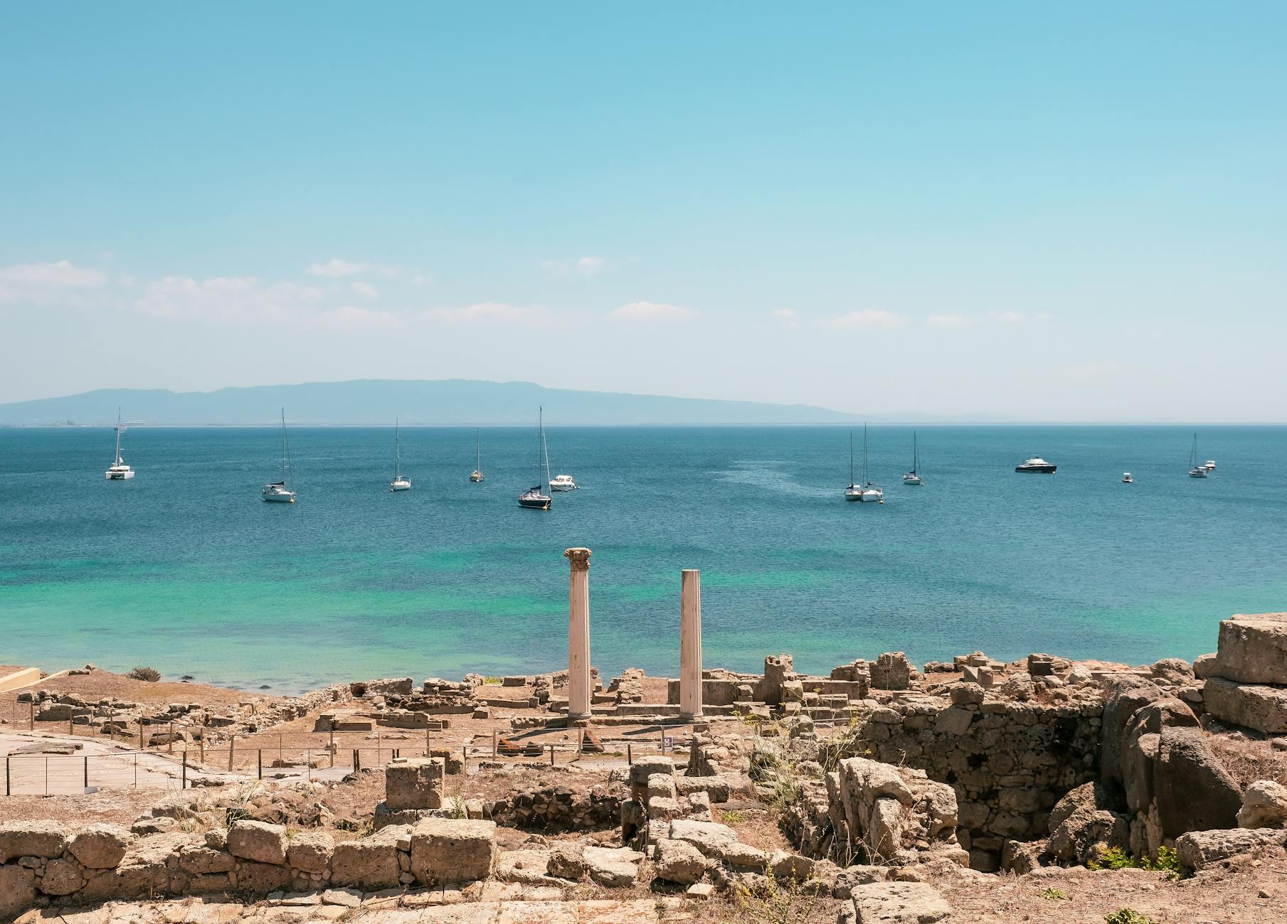 Ruinas antiguas en la costa de Cerdeña con yates en el Mediterráneo