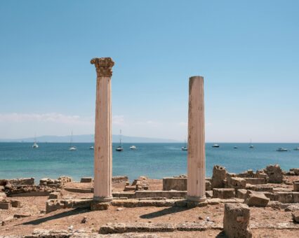 Columnas romanas del yacimiento de Nora en la costa de Cerdeña con yates al fondo
