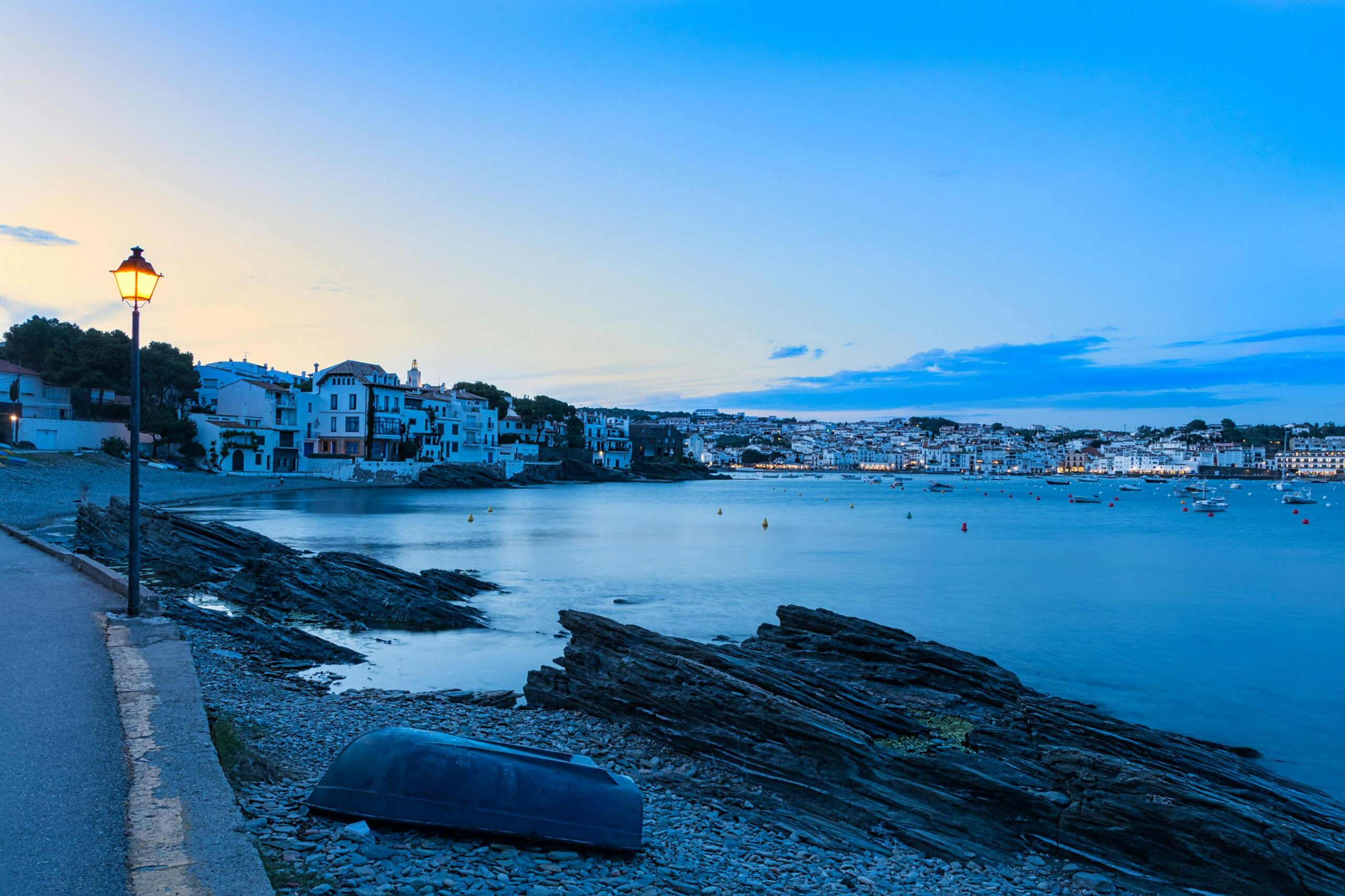 Escena nocturna tranquila de Cadaques con casas iluminadas junto a la bahia