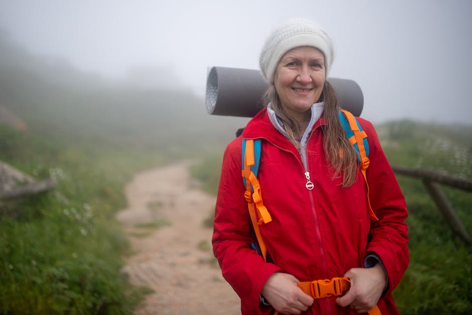 Peregrina sonriente caminando con mochila por sendero del Camino de Santiago