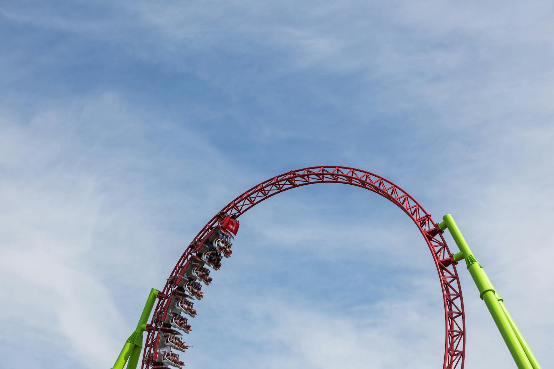 Montaña rusa haciendo un loop bajo un cielo azul en un parque de atracciones