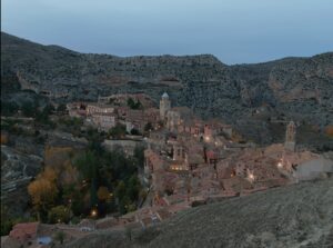 Vista aérea de Teruel al atardecer, con su paisaje urbano histórico y las montañas al fondo