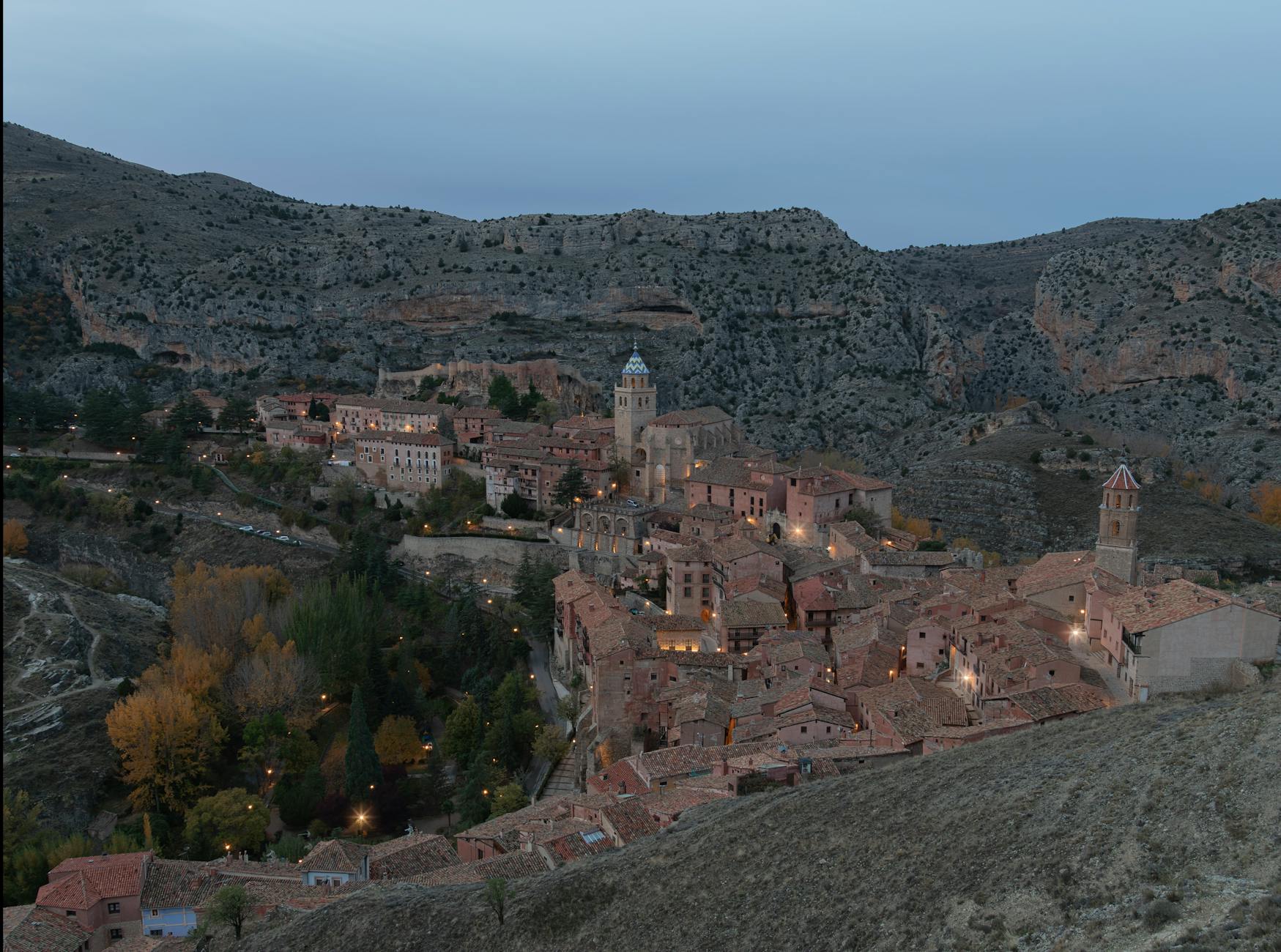Vista aérea de Teruel al atardecer, con su paisaje urbano histórico y las montañas al fondo