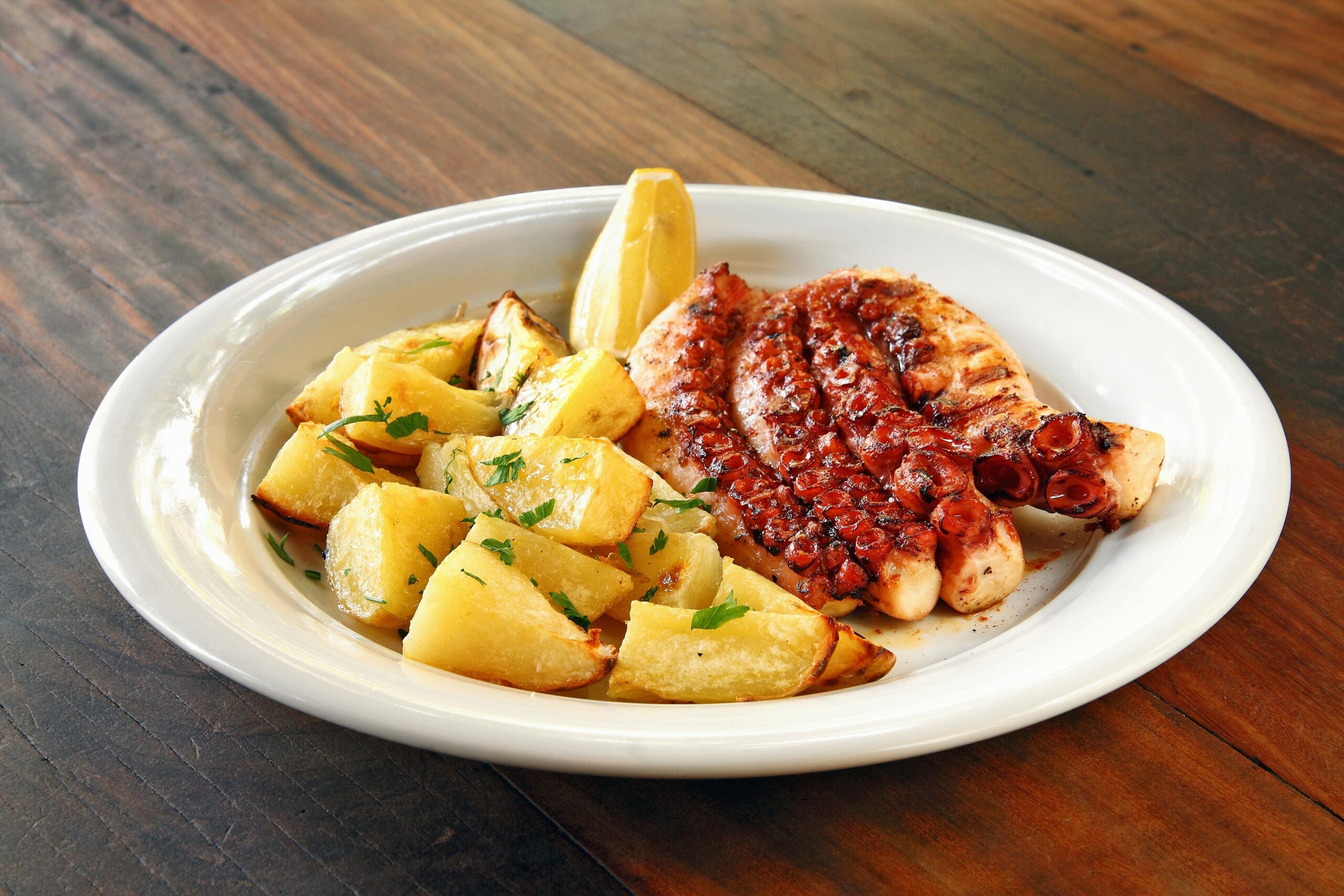 Pulpo a la gallega con cachelos y pimenton sobre tabla de madera