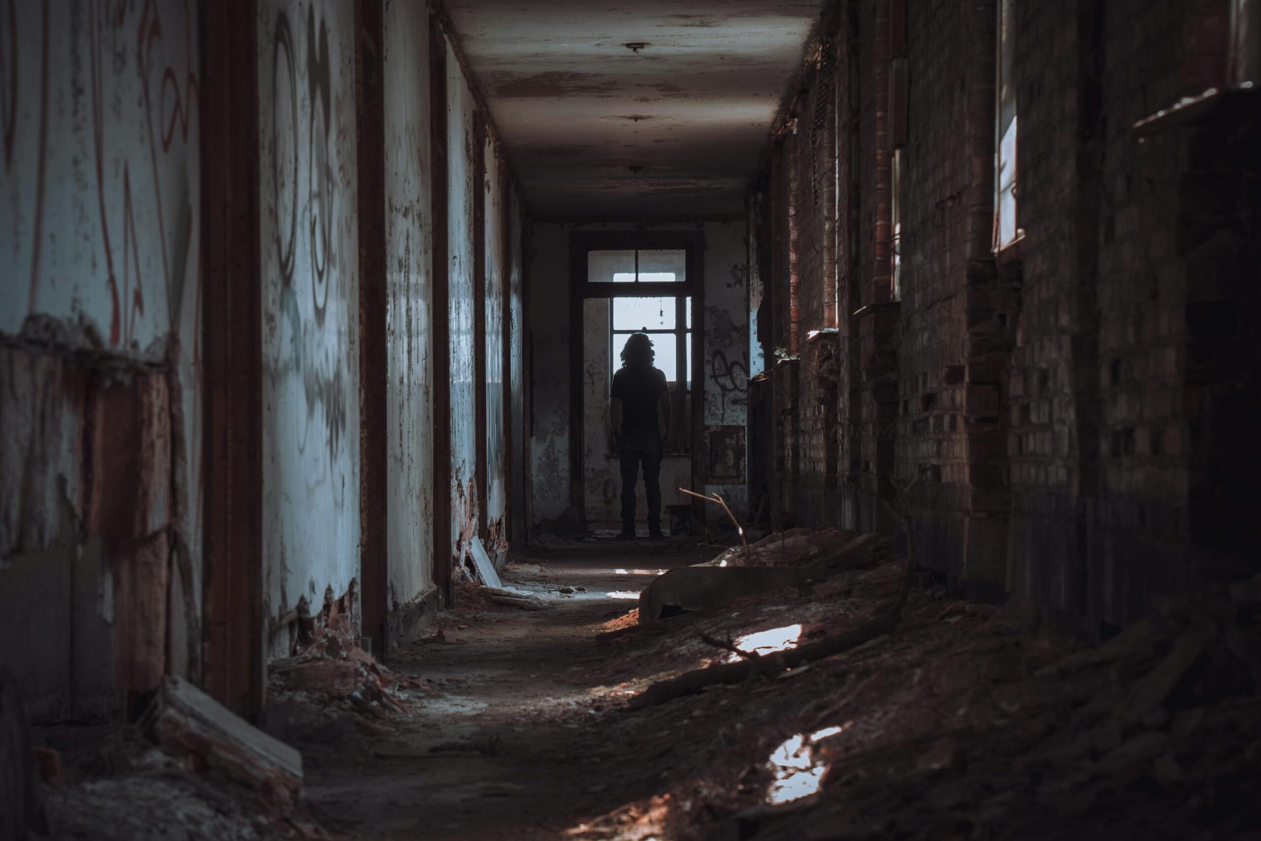 Figura solitaria en pasillo oscuro con atmosfera inquietante