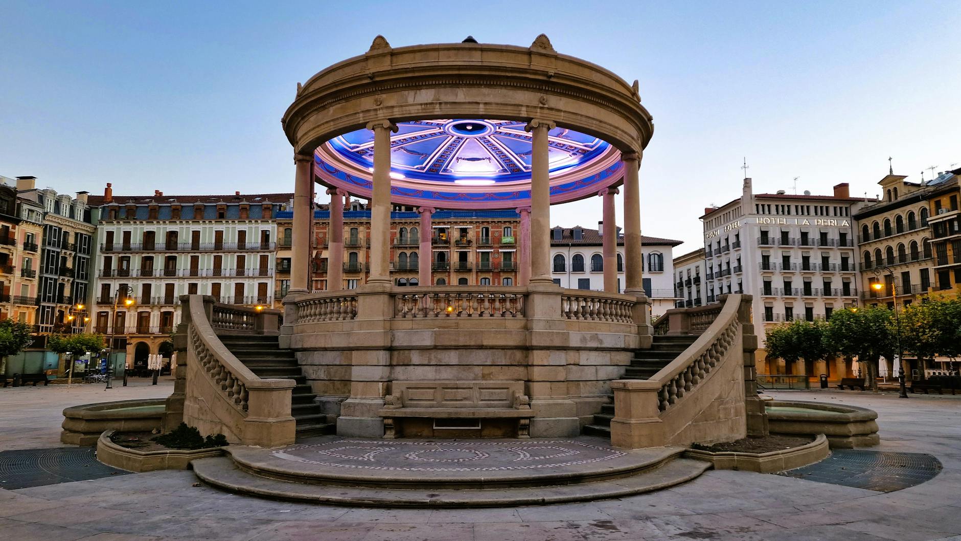 Kiosko de piedra iluminado en la plaza del Castillo de Pamplona al atardecer