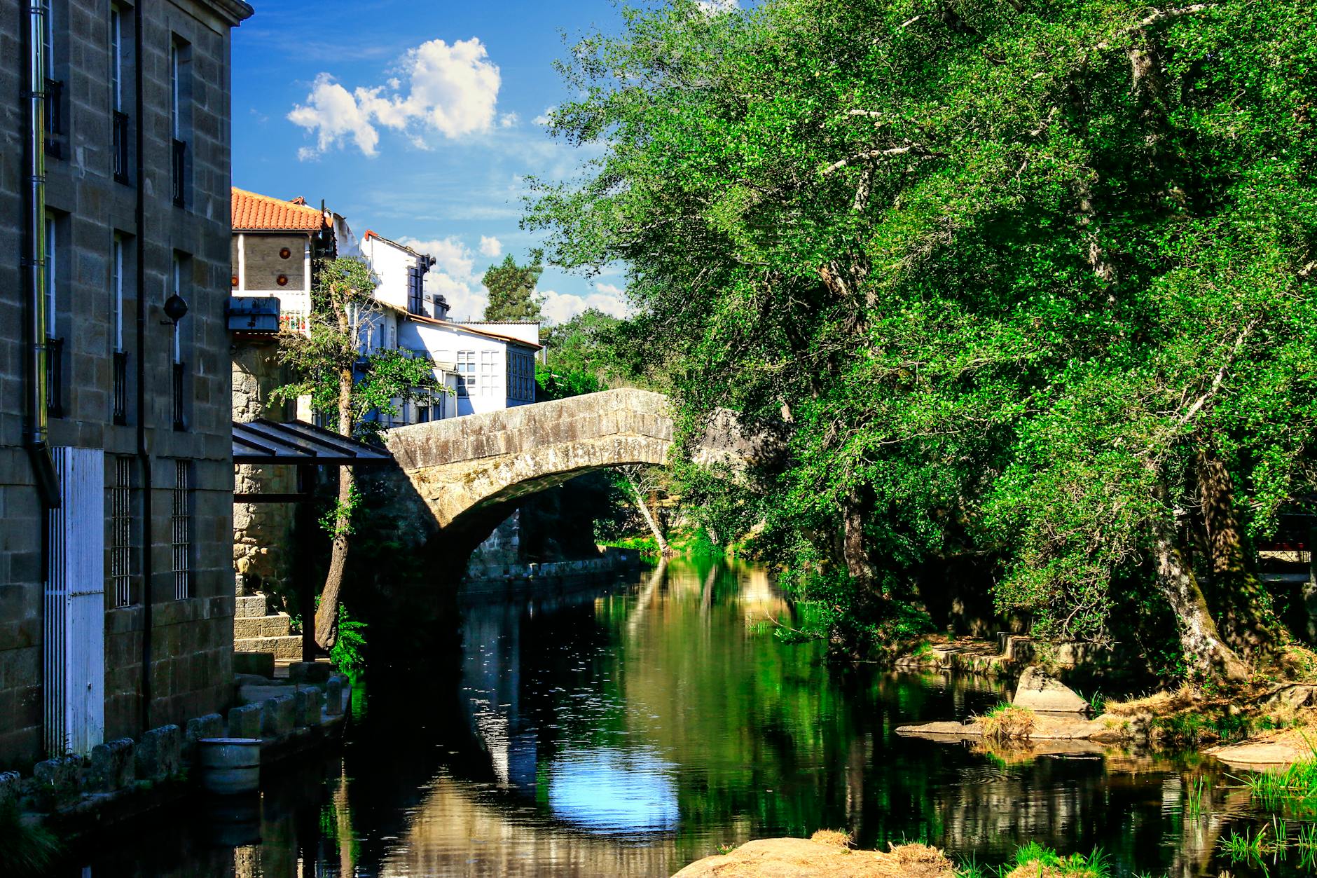 Puente de piedra medieval sobre el rio Arnoia en Allariz Ourense reflejado en aguas tranquilas