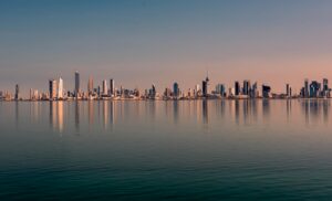 Skyline de Kuwait City al atardecer reflejado en el agua con arquitectura moderna