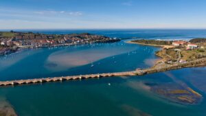 Vista aérea de la costa de Cantabria con puente y pueblo marinero al fondo