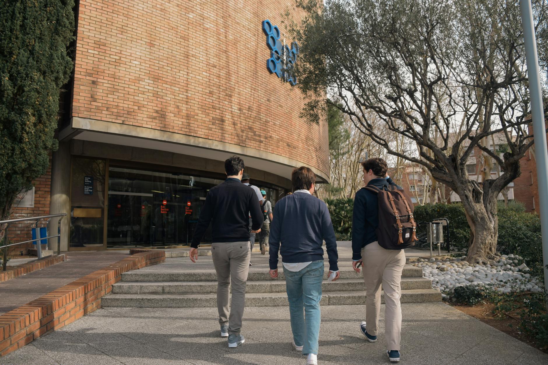 Tres estudiantes acercandose a la entrada de un edificio universitario en Barcelona