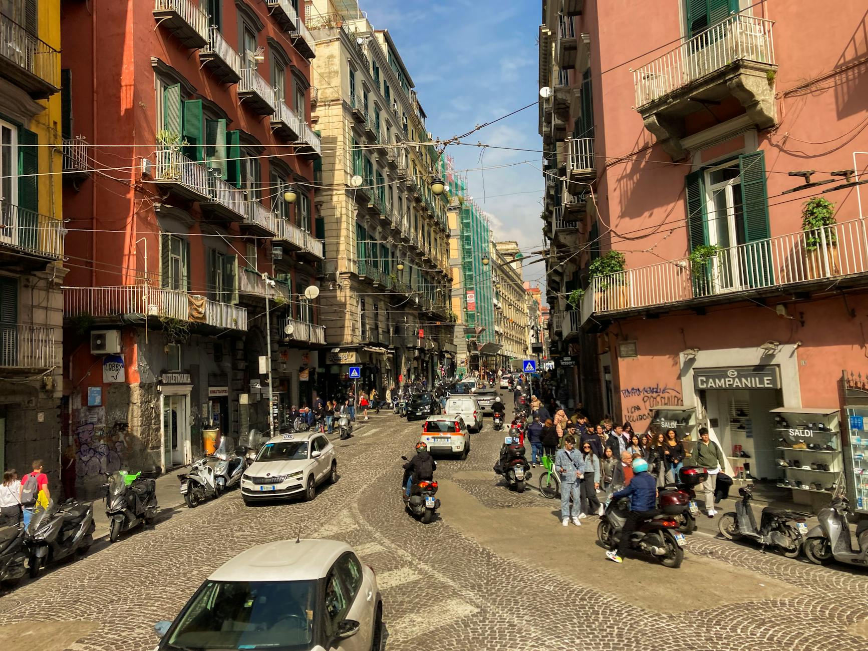 Calle concurrida de Napoles con scooters y peatones en un dia soleado