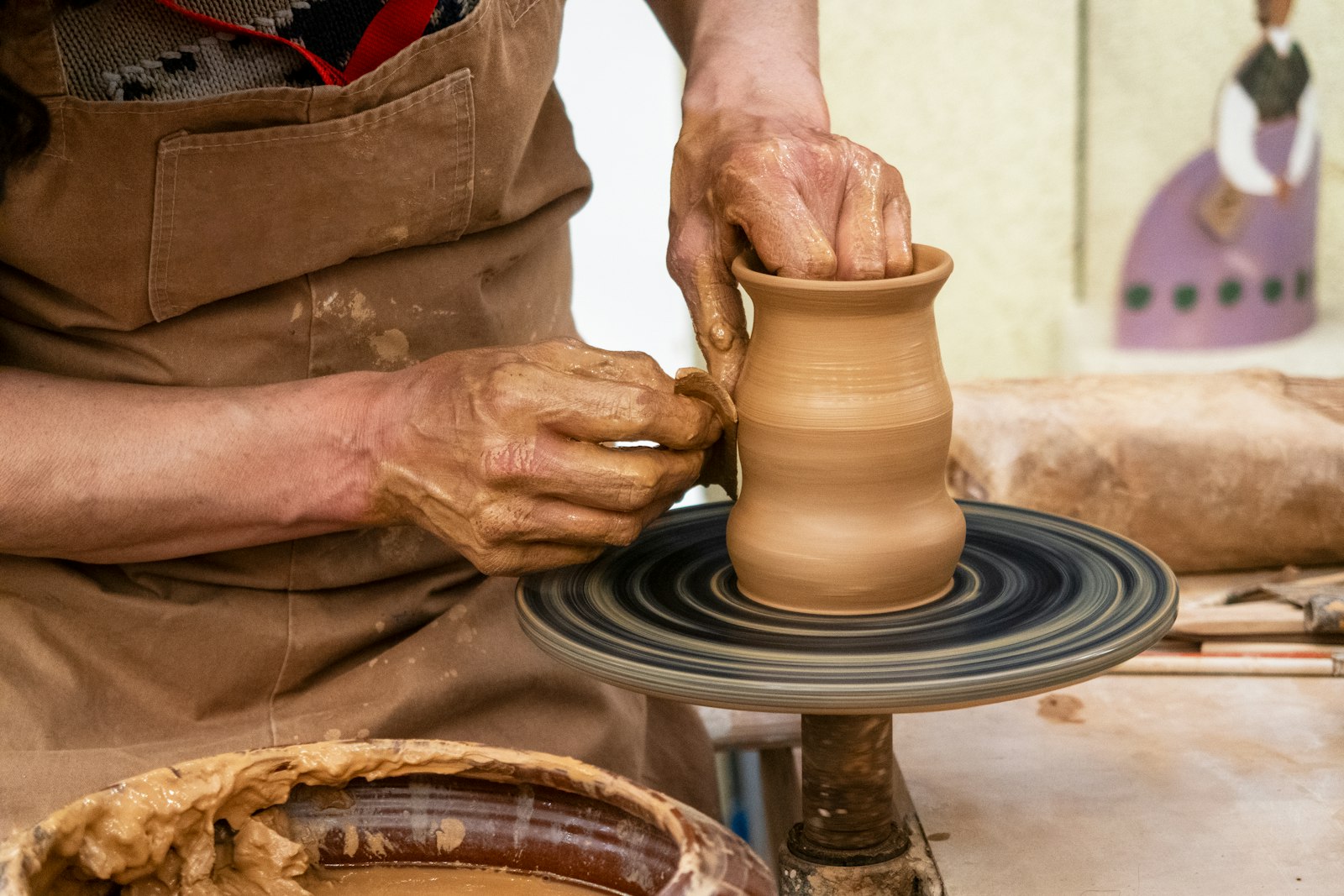 Manos modelando arcilla en un torno de alfarero en un taller de ceramica