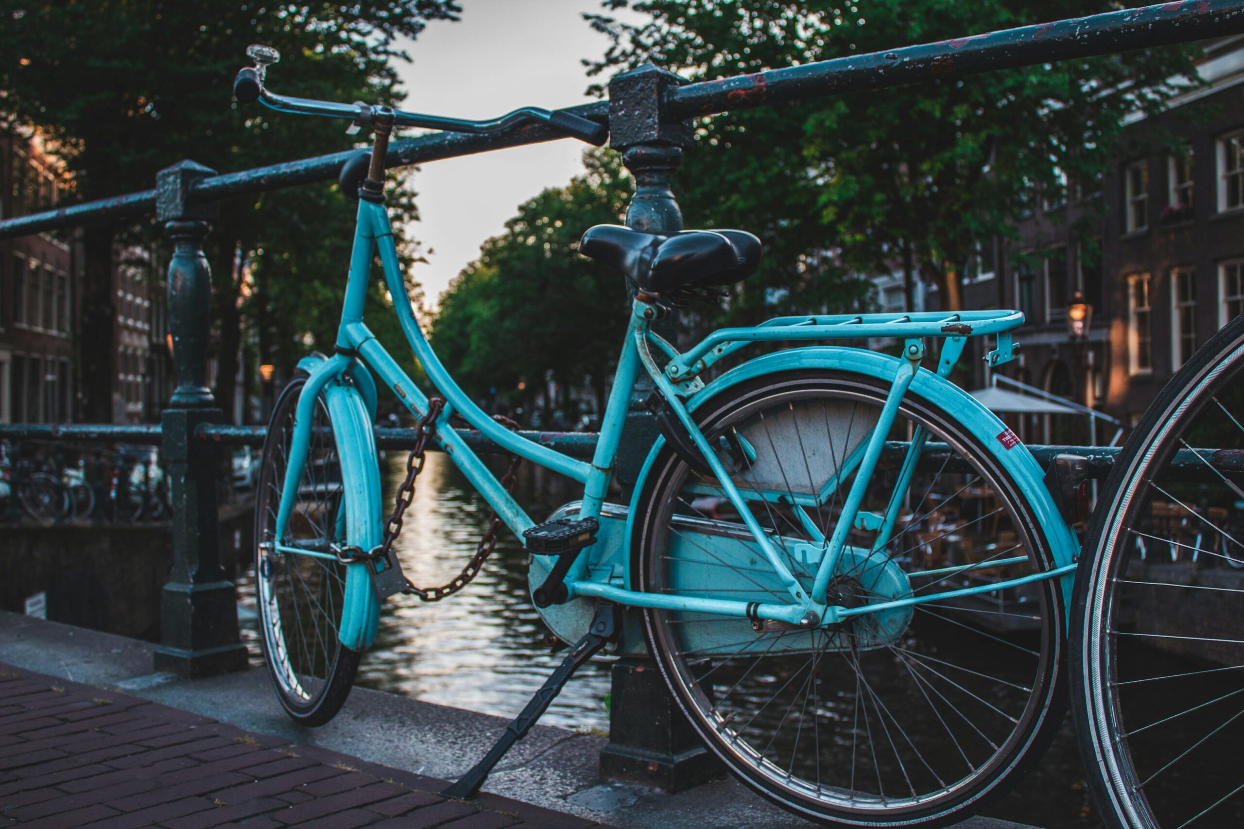 Bicicleta azul aparcada en un puente sobre canal en Amsterdam