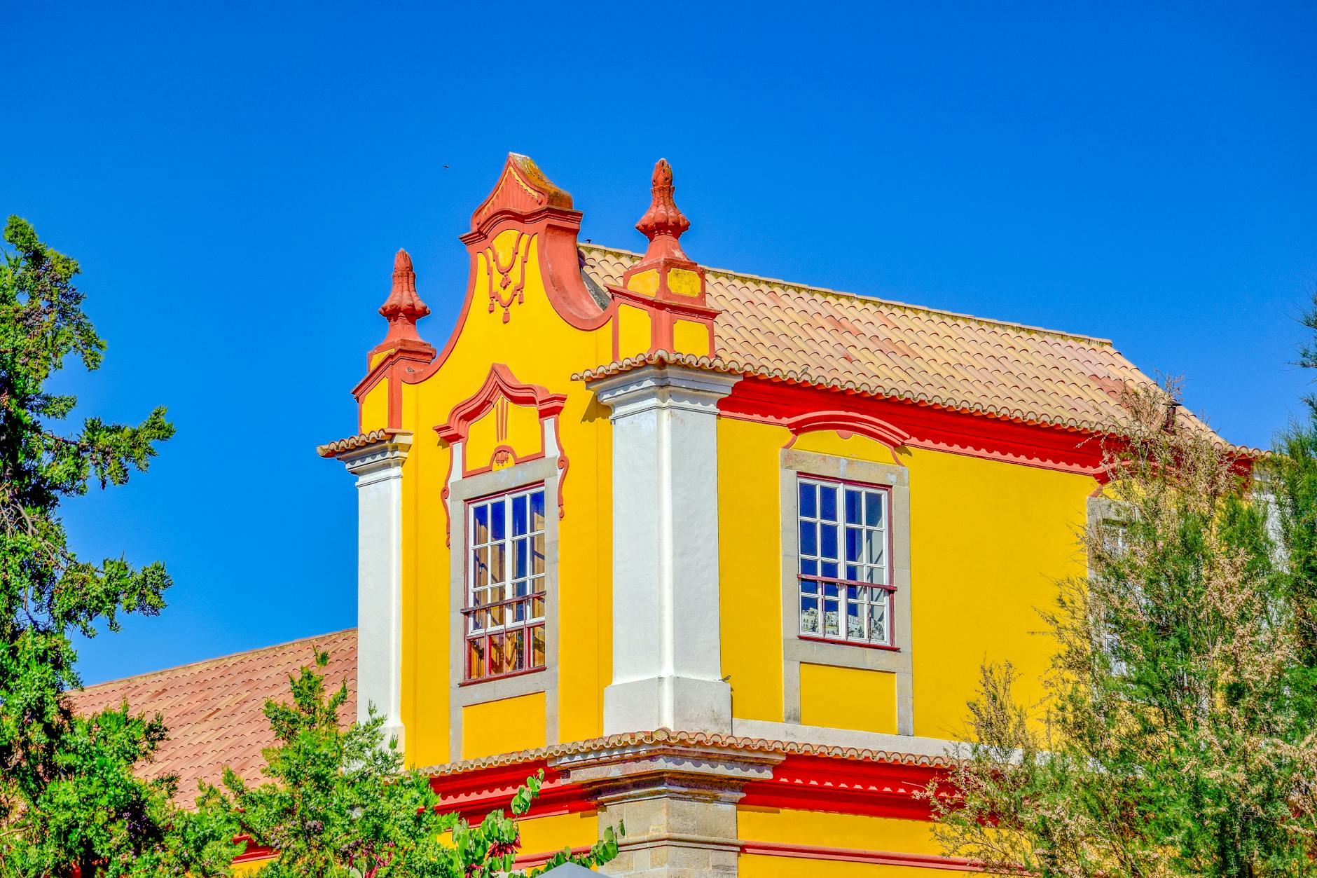 Fachada amarilla de un edificio historico en Tavira, Portugal, bajo cielo azul