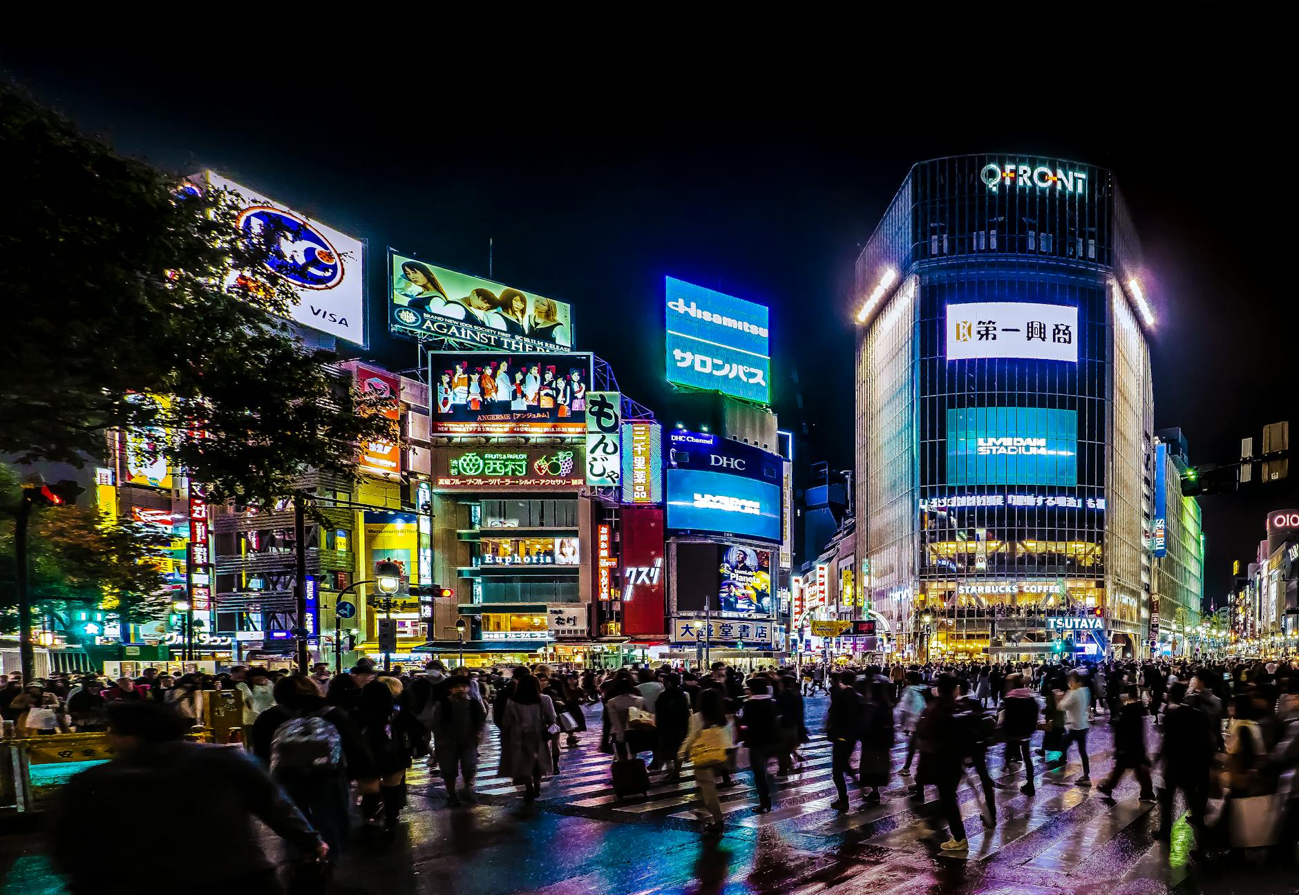 Cruce de Shibuya en Tokio iluminado por la noche con multitud de peatones