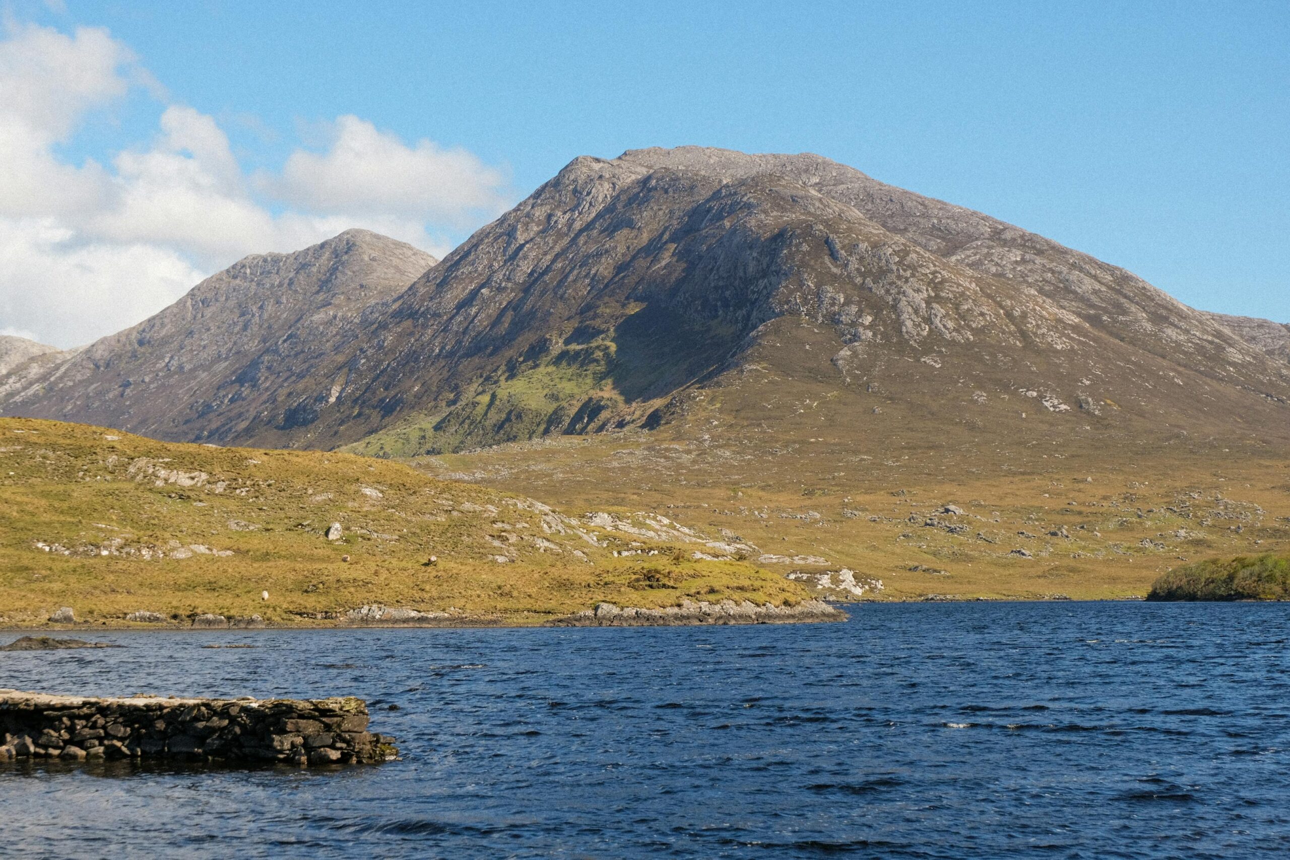 Montañas y lago tranquilo de Connemara bajo cielo azul, oeste de Irlanda