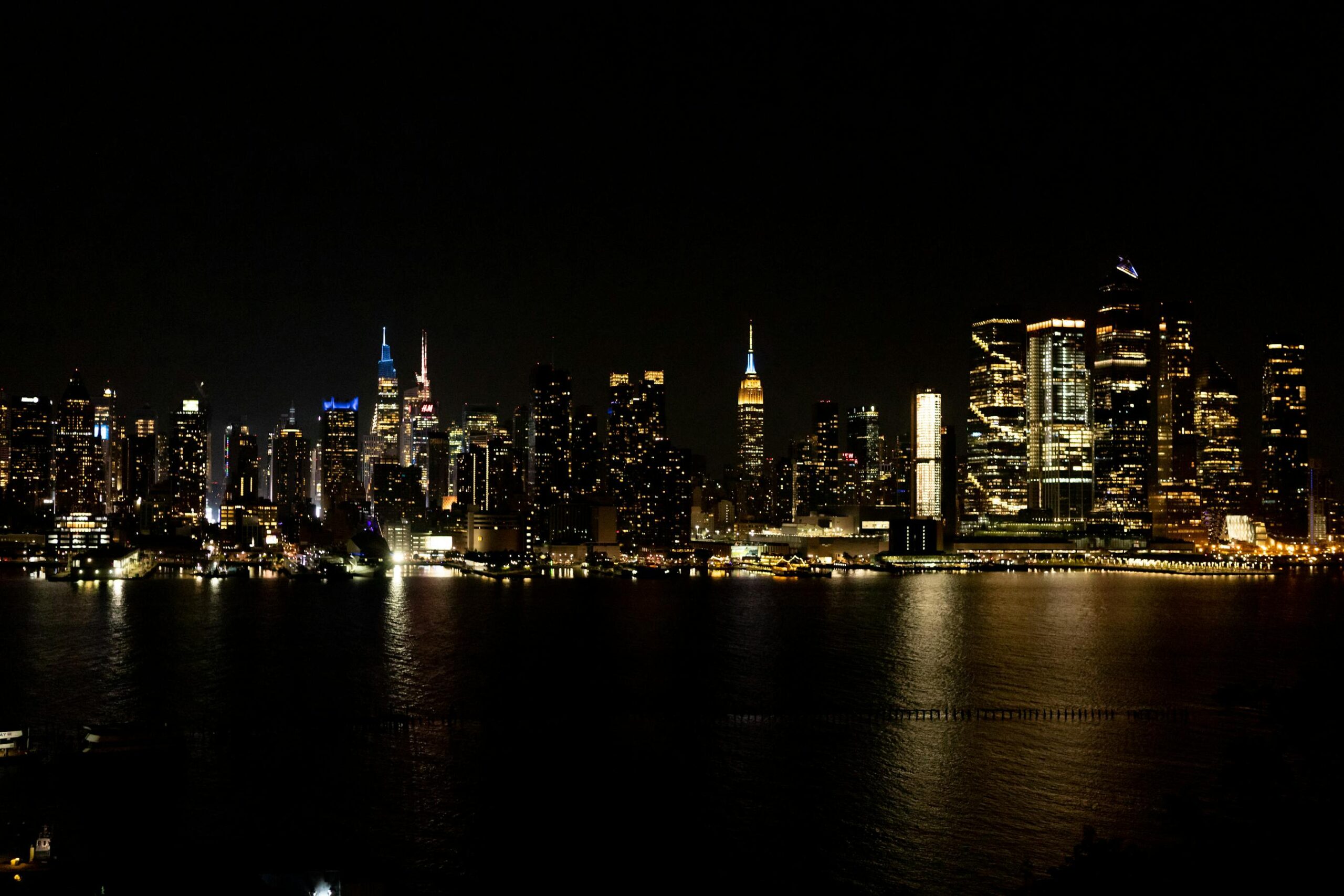 Skyline iluminado de Nueva York reflejandose en el agua por la noche