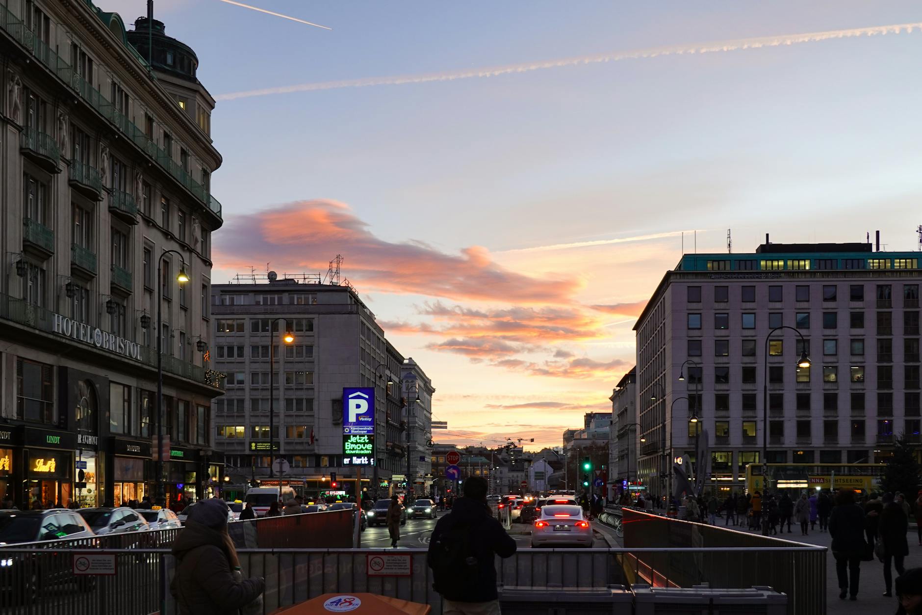 Calle de Viena al atardecer con coches y peatones, zona de aparcamiento regulado