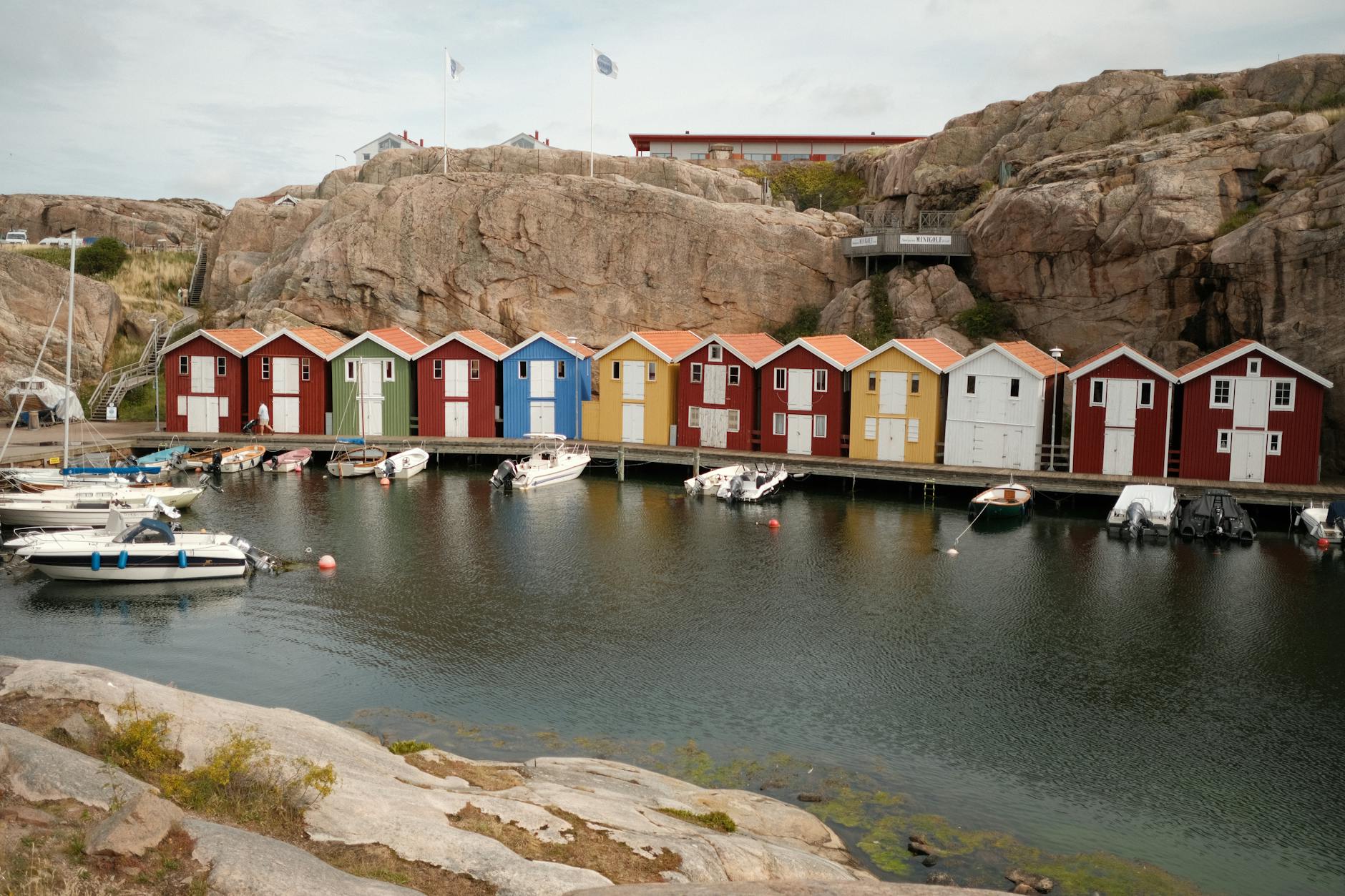 Casetas de pescadores de colores en un puerto sueco con barcos amarrados a lo largo de la orilla
