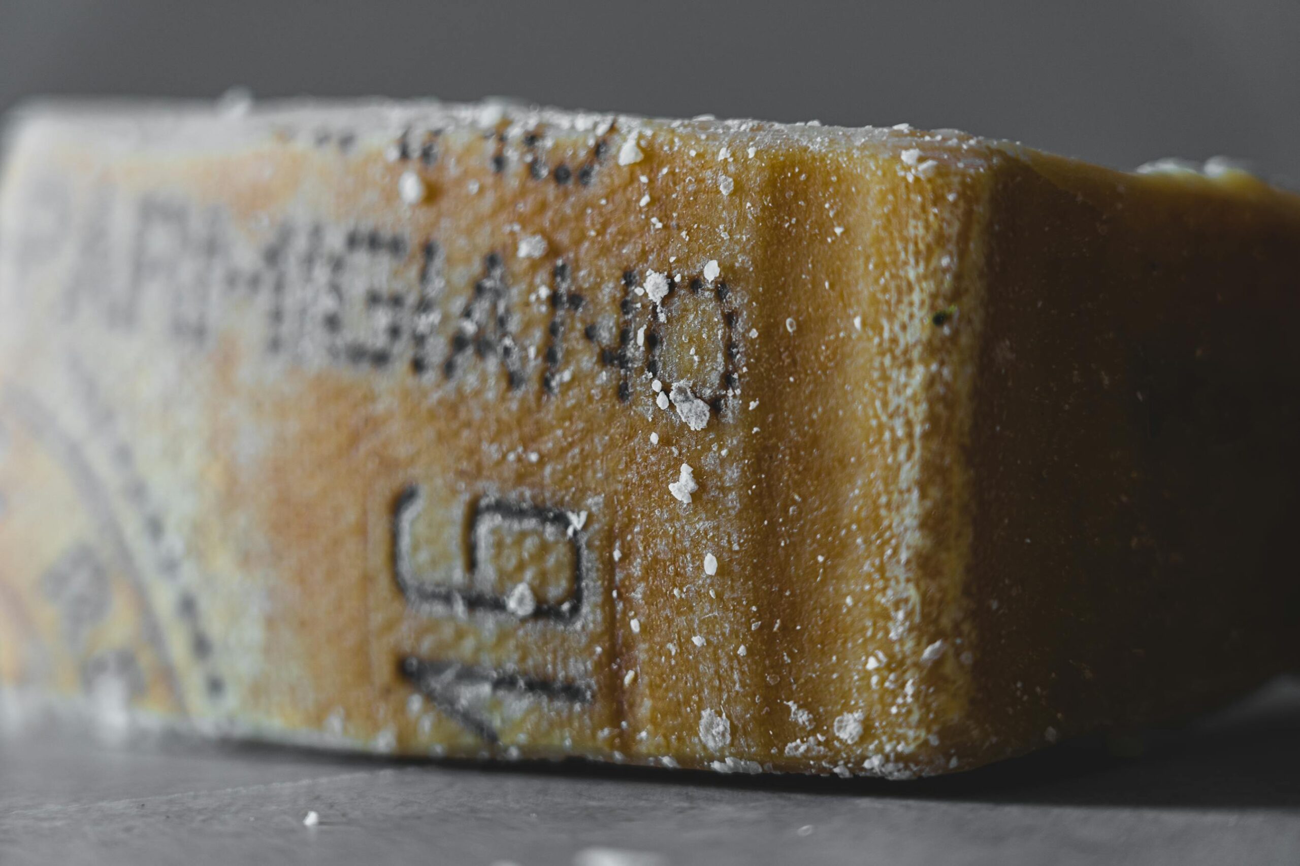 Bloque de Parmigiano Reggiano envejecido con textura y cristales de sal, queso italiano