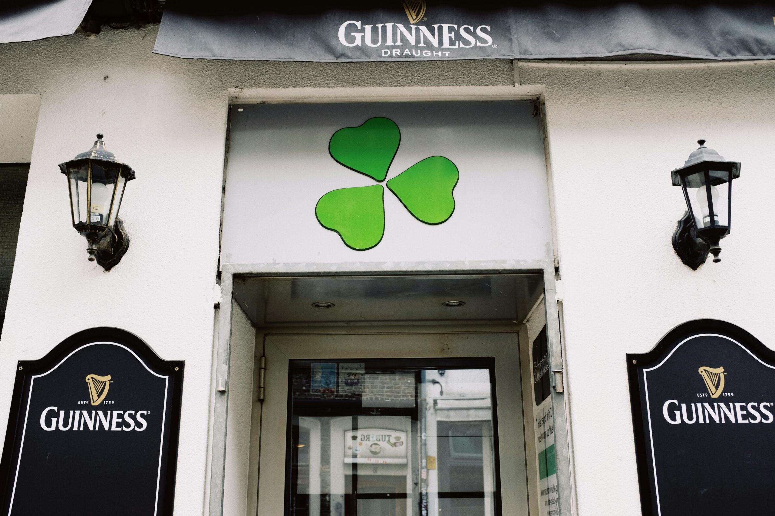 Exterior de pub irlandes con trebol y cartel Guinness invitando a entrar