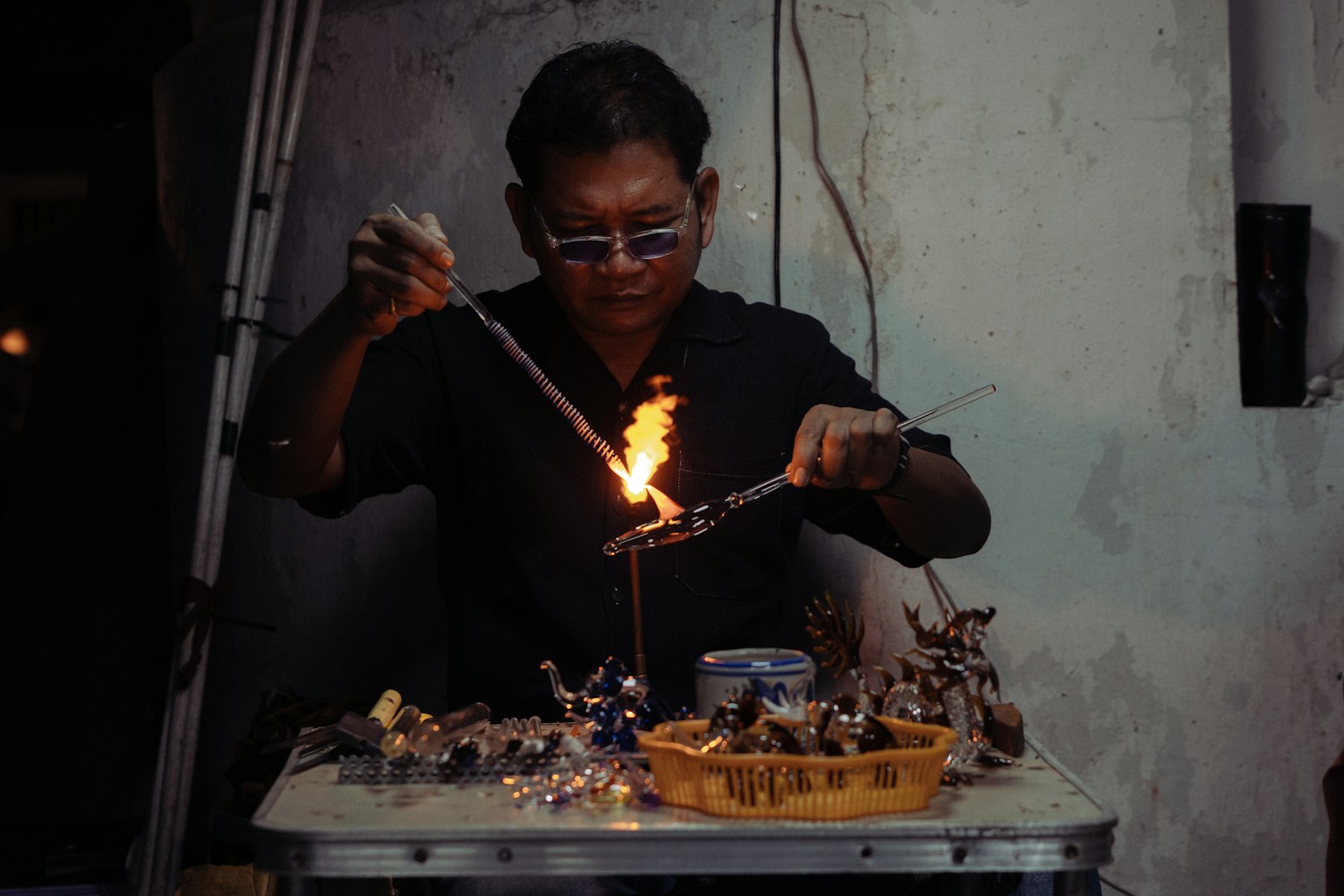 Artesano trabajando vidrio caliente en un taller con la llama del horno