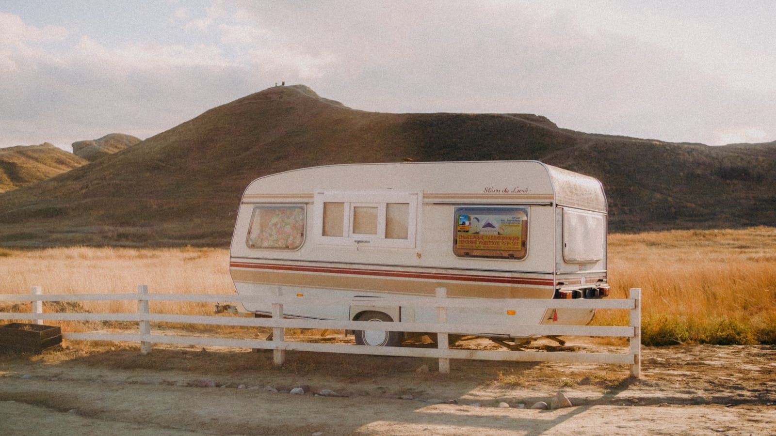 Cámper vintage estacionado en un prado con colinas montañosas al fondo